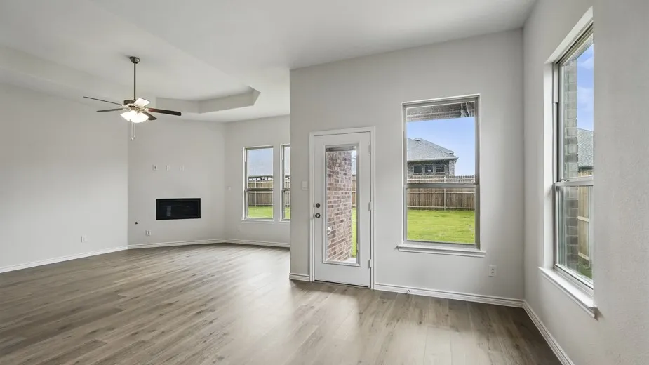 Spacious living area featuring wood-finish flooring, a contemporary ceiling fan, and a built-in electric fireplace