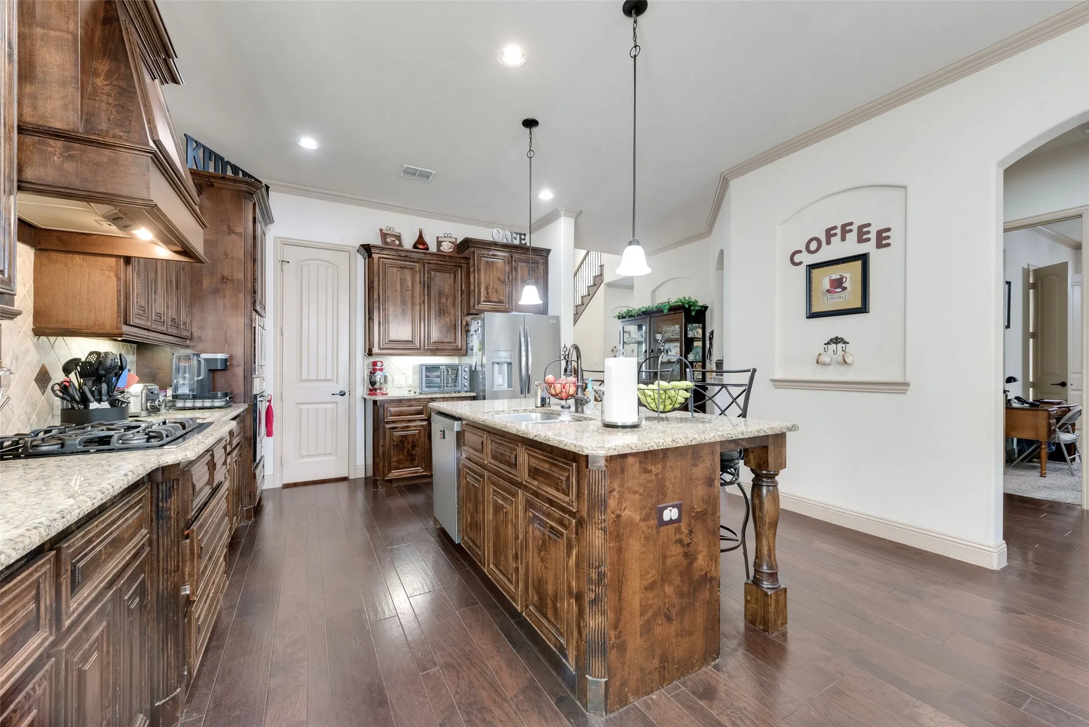 Kitchen with  pendant lighting, light stone countertops, and custom range hood