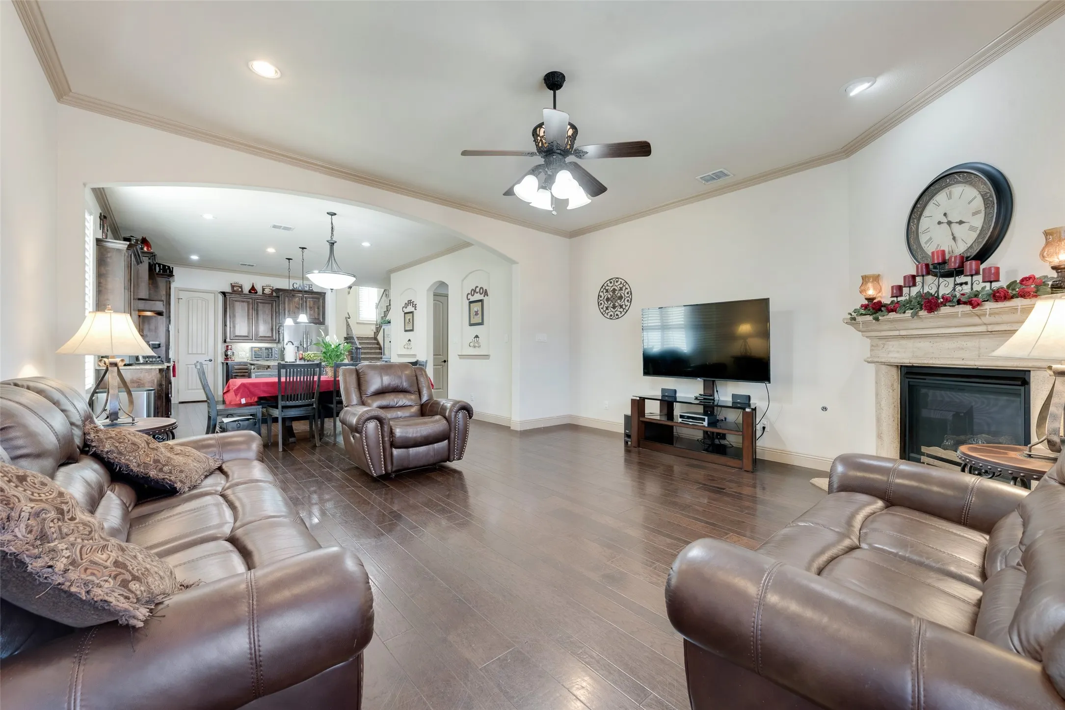 Living room featuring crown molding, a fireplace, dark hardwood / wood-style floors, and ceiling fan