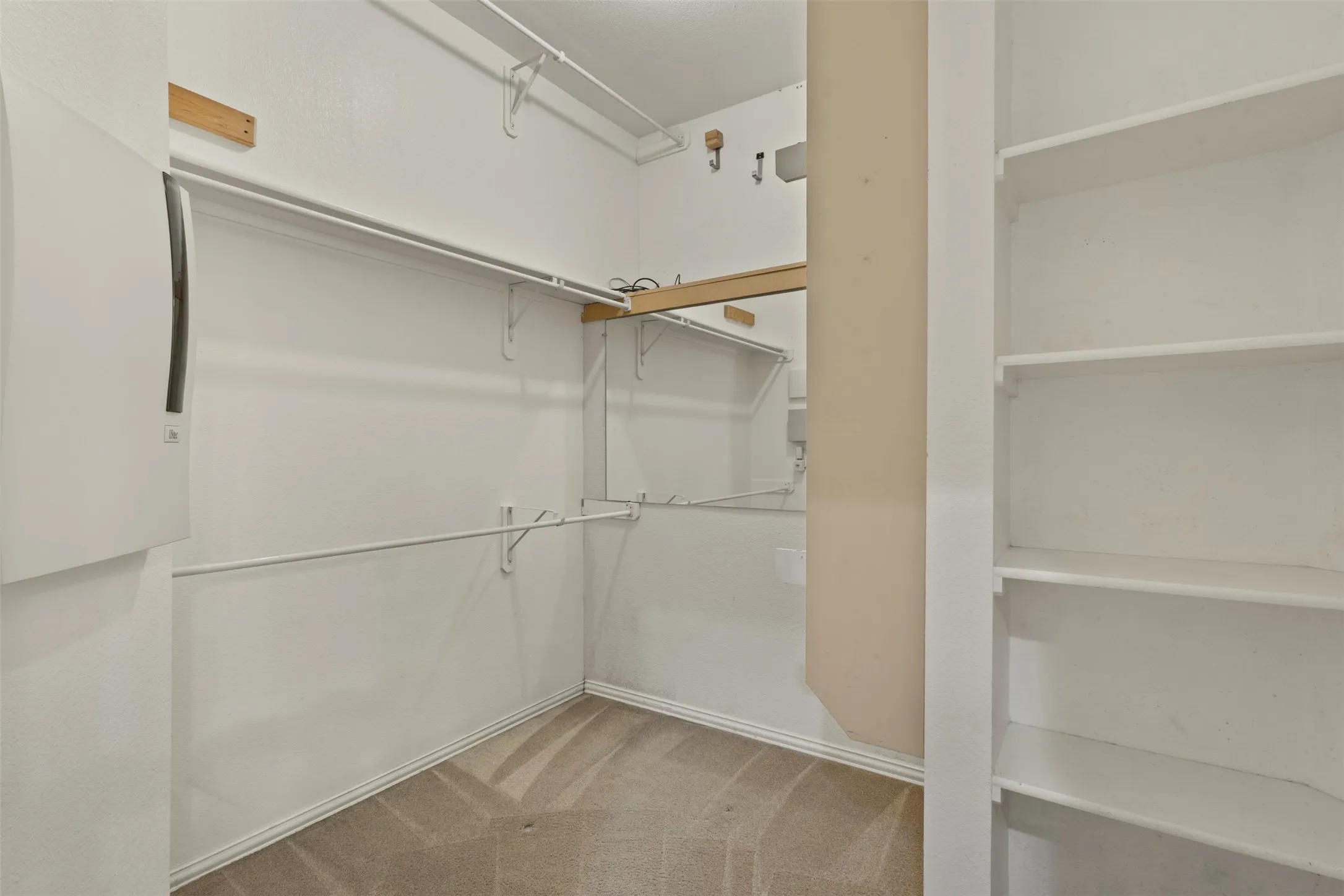 Built-in shelving, mirrored wall, integrated hanging rods, and carpet flooring