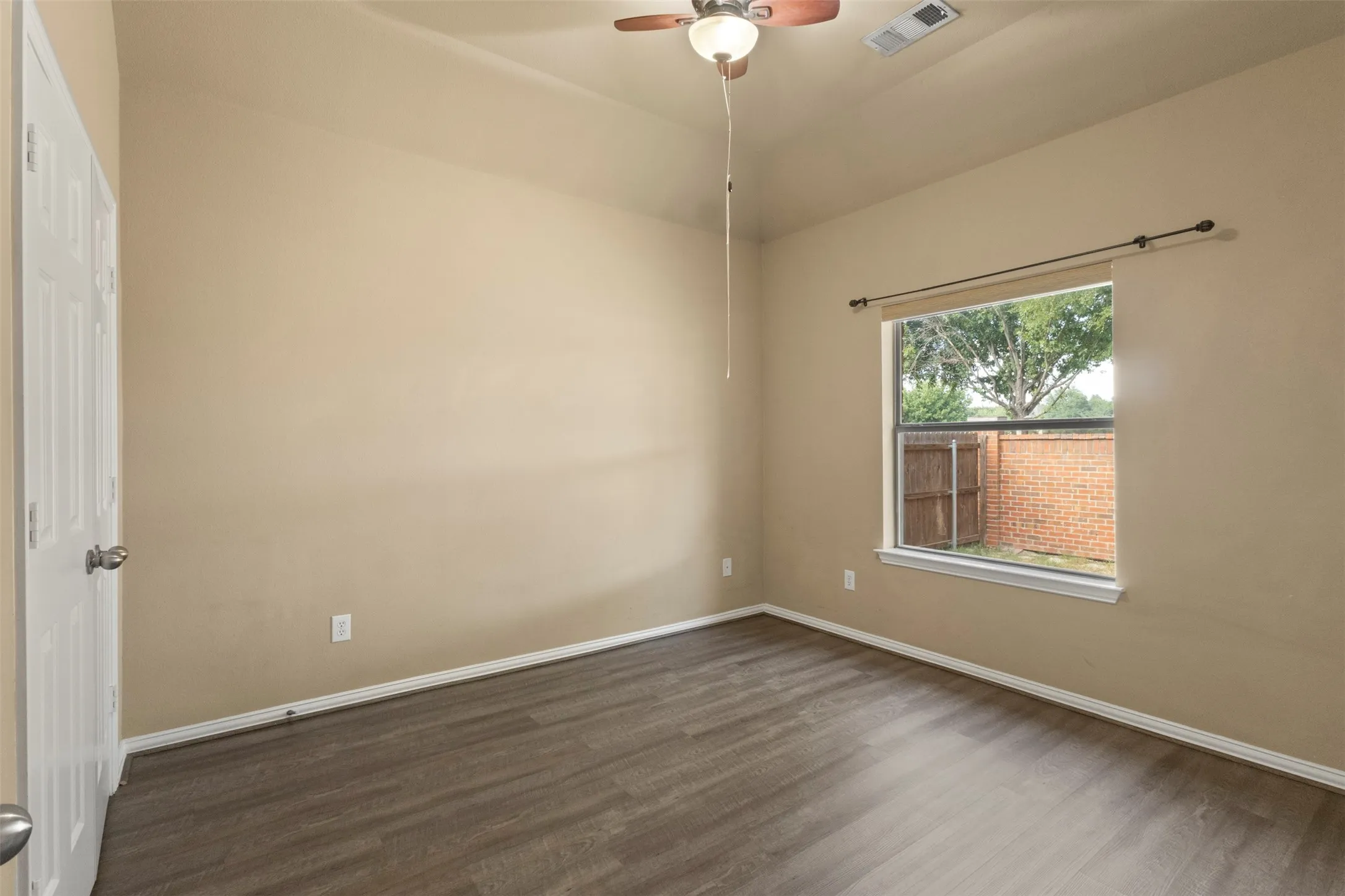 Wood-finish flooring, neutral wall tones, ceiling fan, and a window with a durable frame