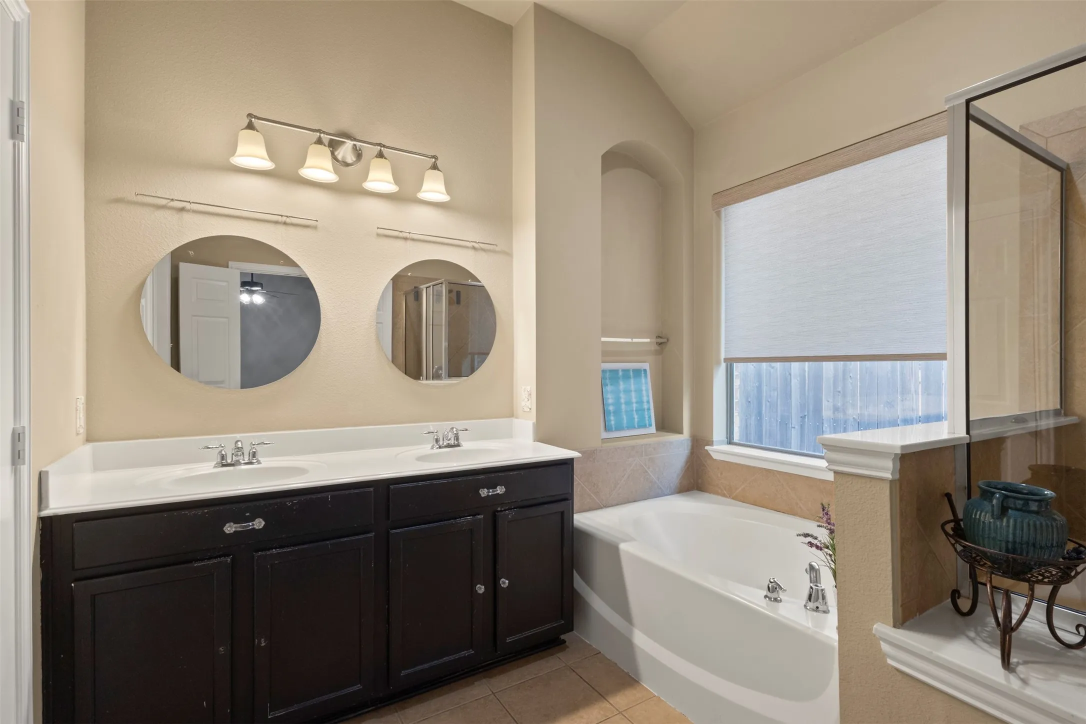Dual round mirrors over a double vanity with dark cabinetry and white countertops
