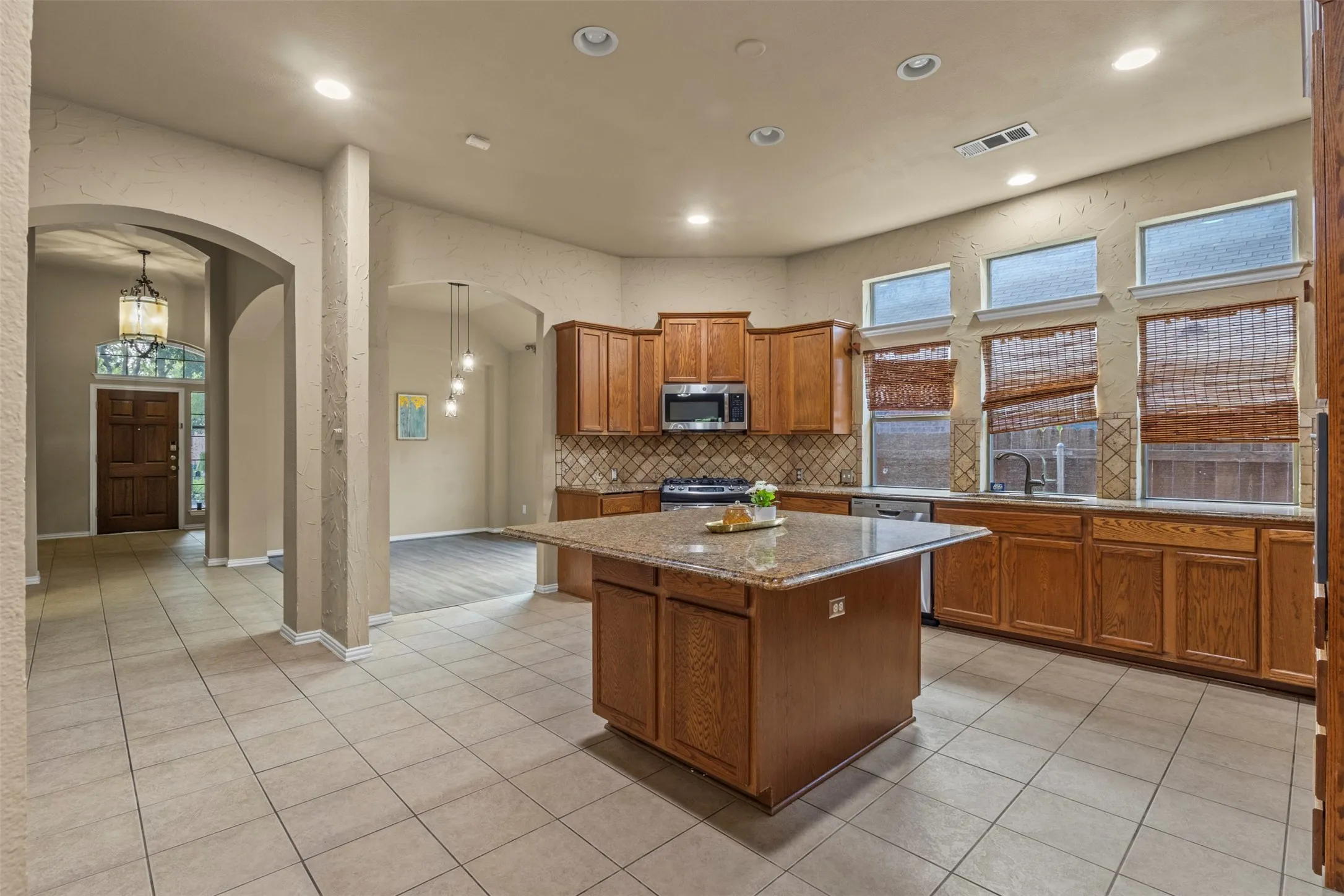 Kitchen featuring a central island, wood cabinetry, stone countertops, and tile flooring