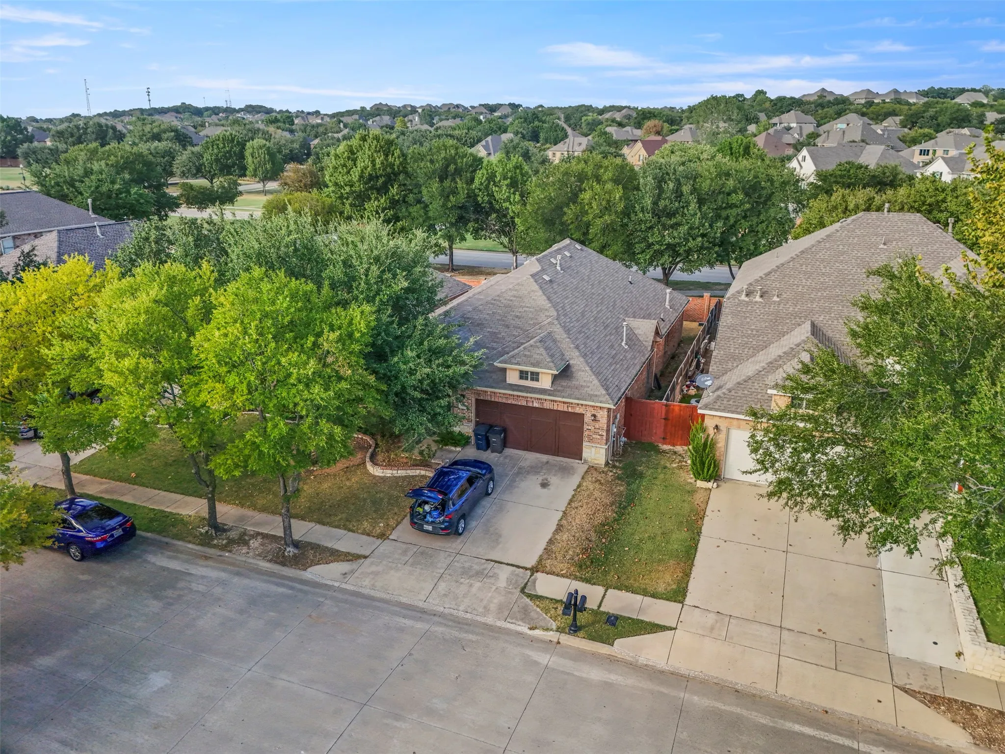Brick-faced exterior with an attached garage, concrete driveway, and mature landscaping