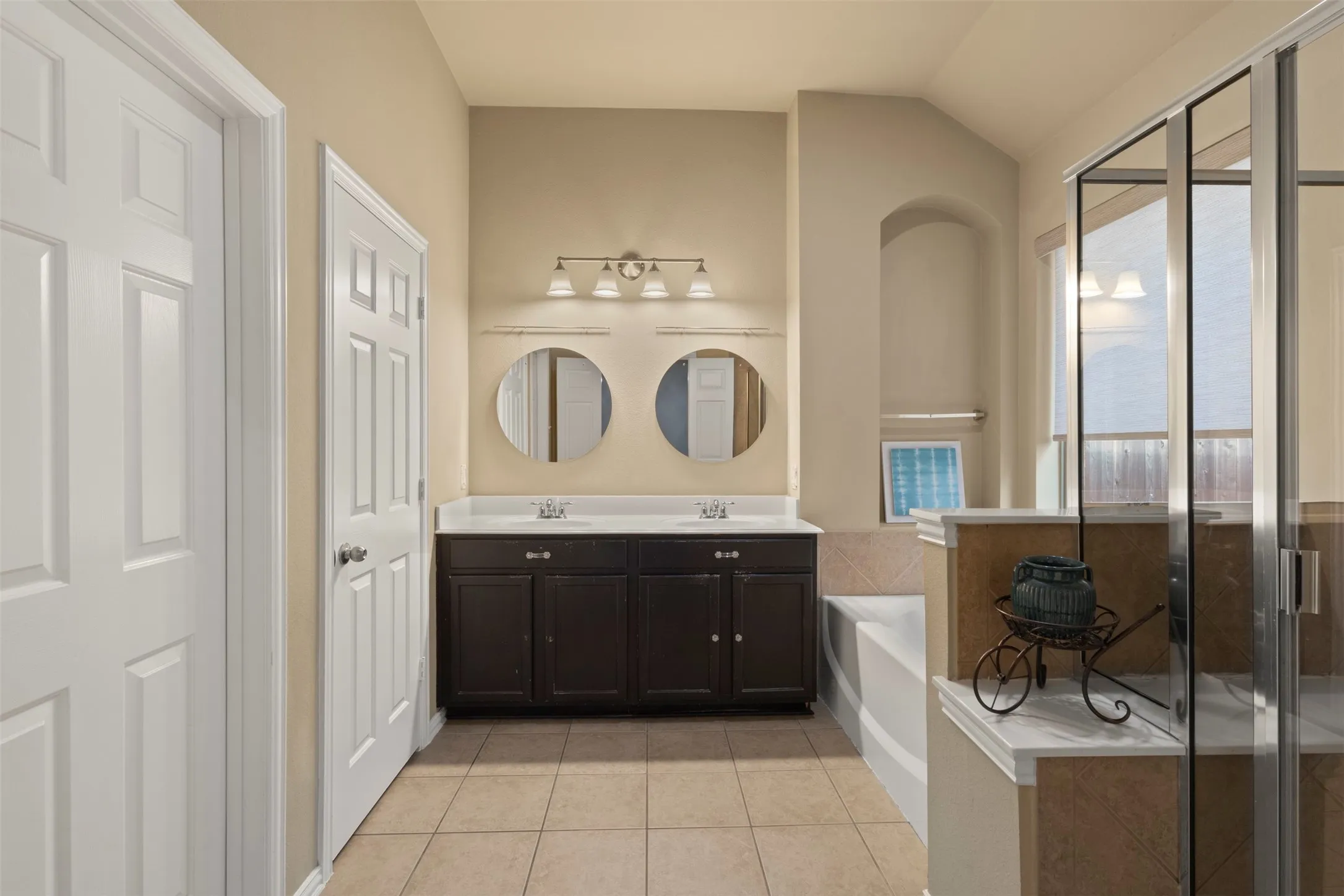Dual vanity with dark wood-finish cabinetry, two round mirrors, and brushed nickel light fixtures
