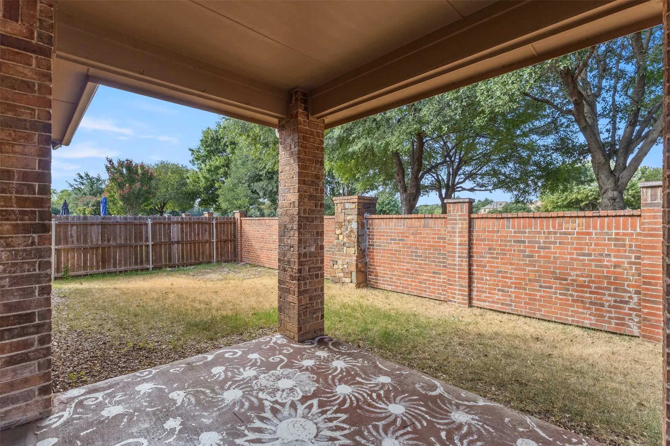 Covered patio with a decorative concrete surface, supported by brick columns