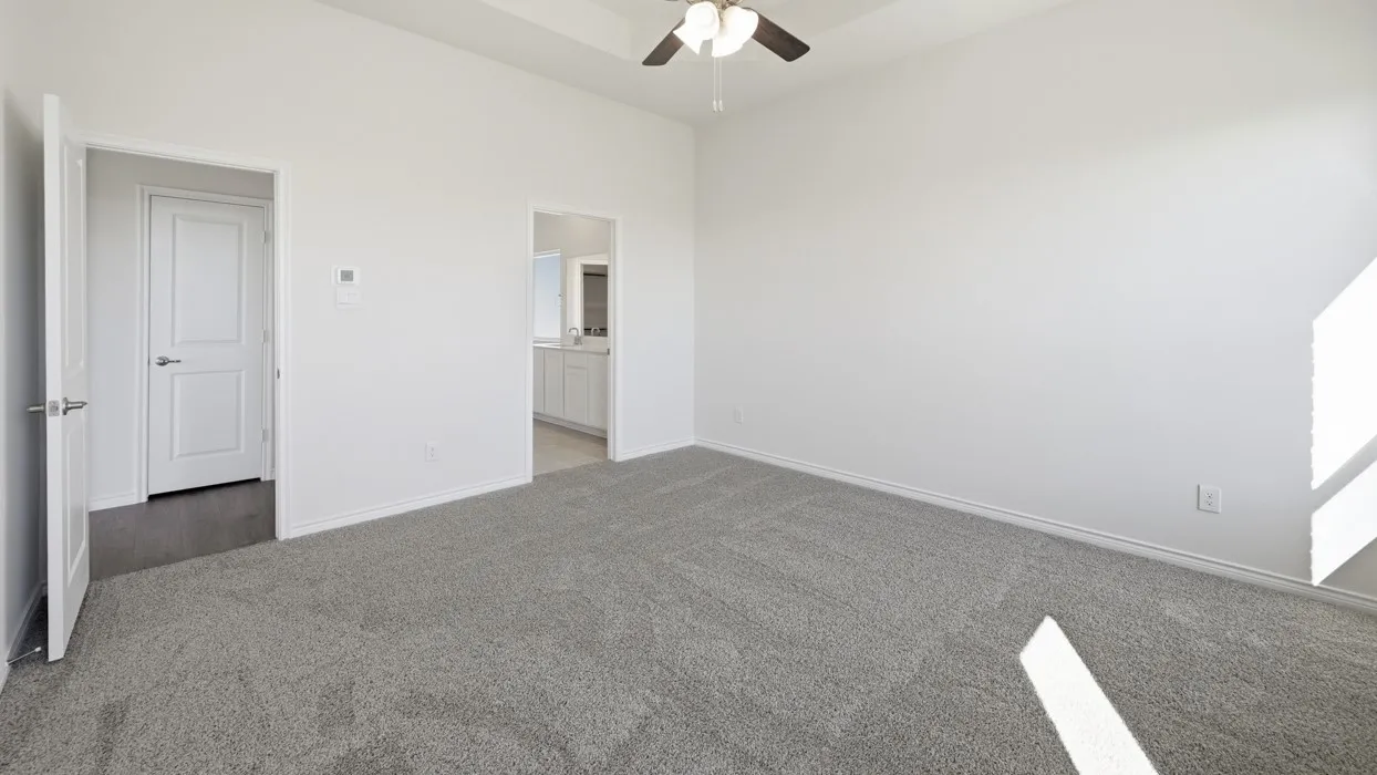 Spacious carpeted room featuring a vaulted ceiling and a ceiling fan
