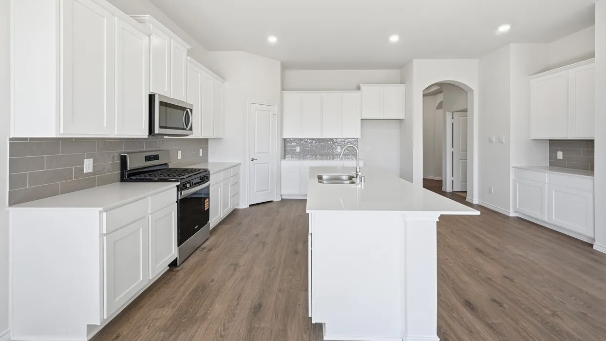 Kitchen featuring white shaker cabinetry, stainless steel appliances, light-toned countertops, gray subway tile backsplash, and wood-finish flooring