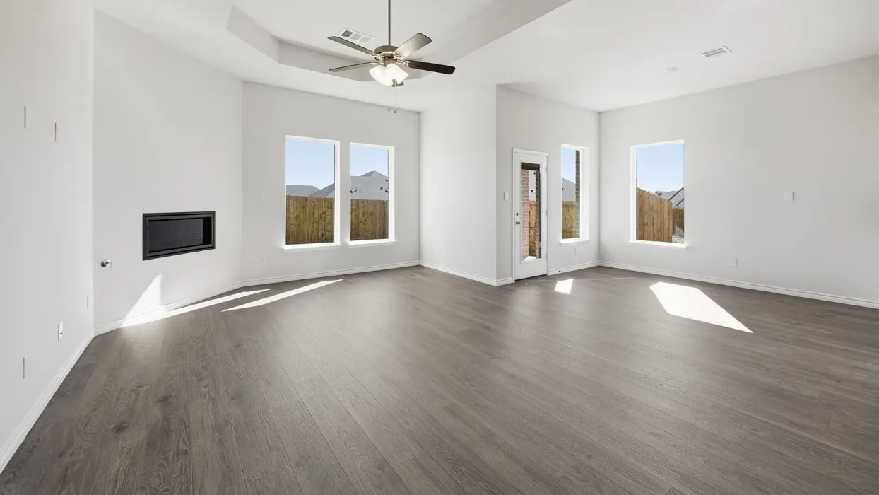 Spacious living area featuring wood-finish flooring, an inset fireplace, and a ceiling fan