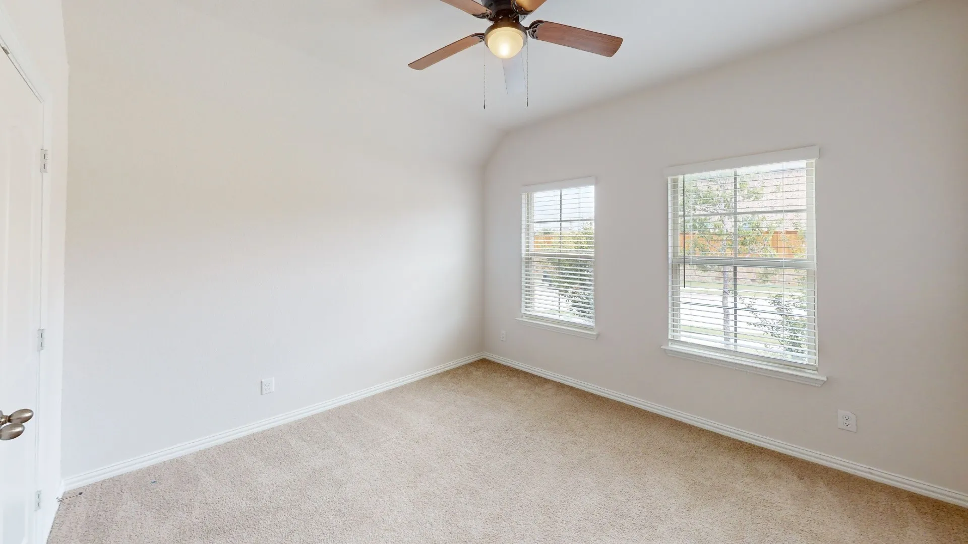 Vaulted ceiling, ceiling fan with integrated lighting, two windows with blinds, carpeted flooring, and white trim