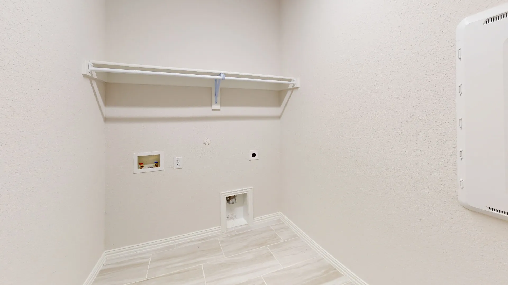 Utility area featuring tile flooring, a built-in shelf, and a clothing rod