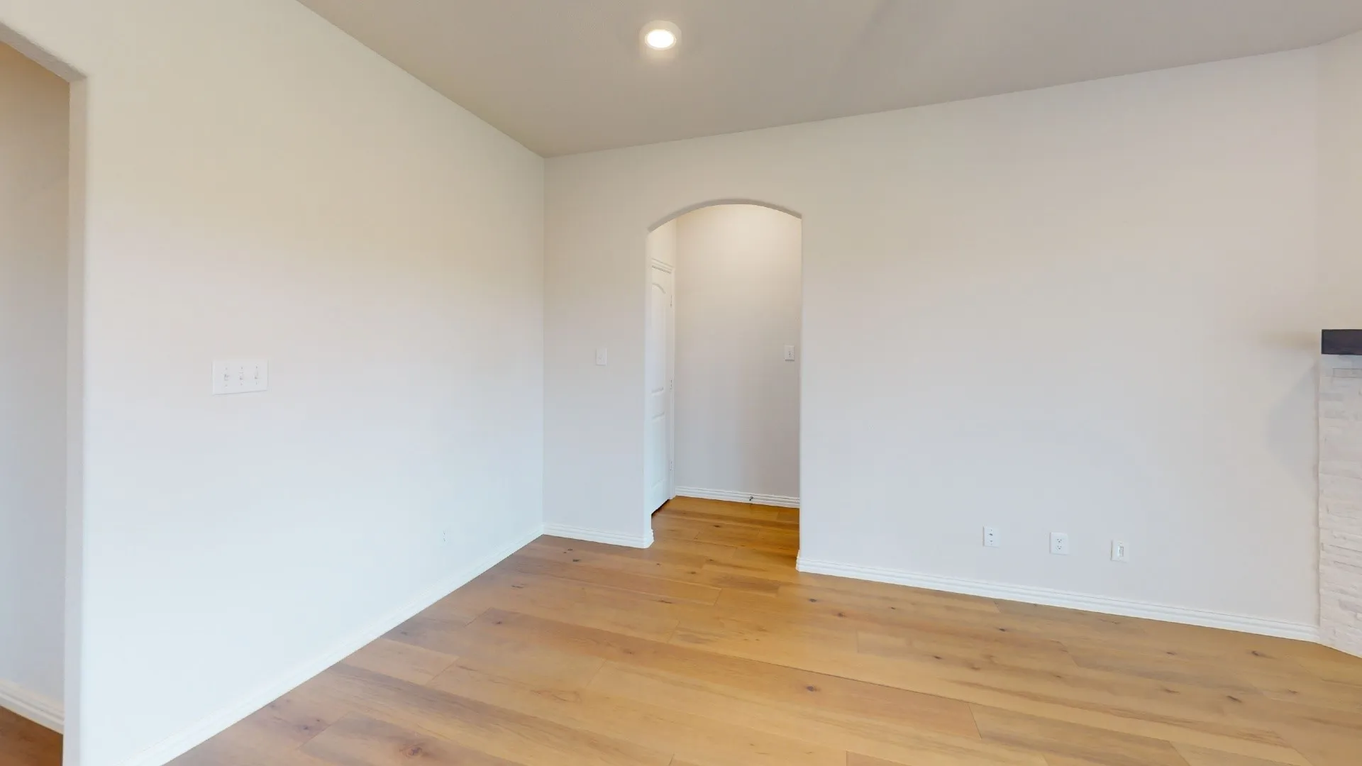 Wood-finish flooring, recessed ceiling lighting, arched doorway, and white painted walls