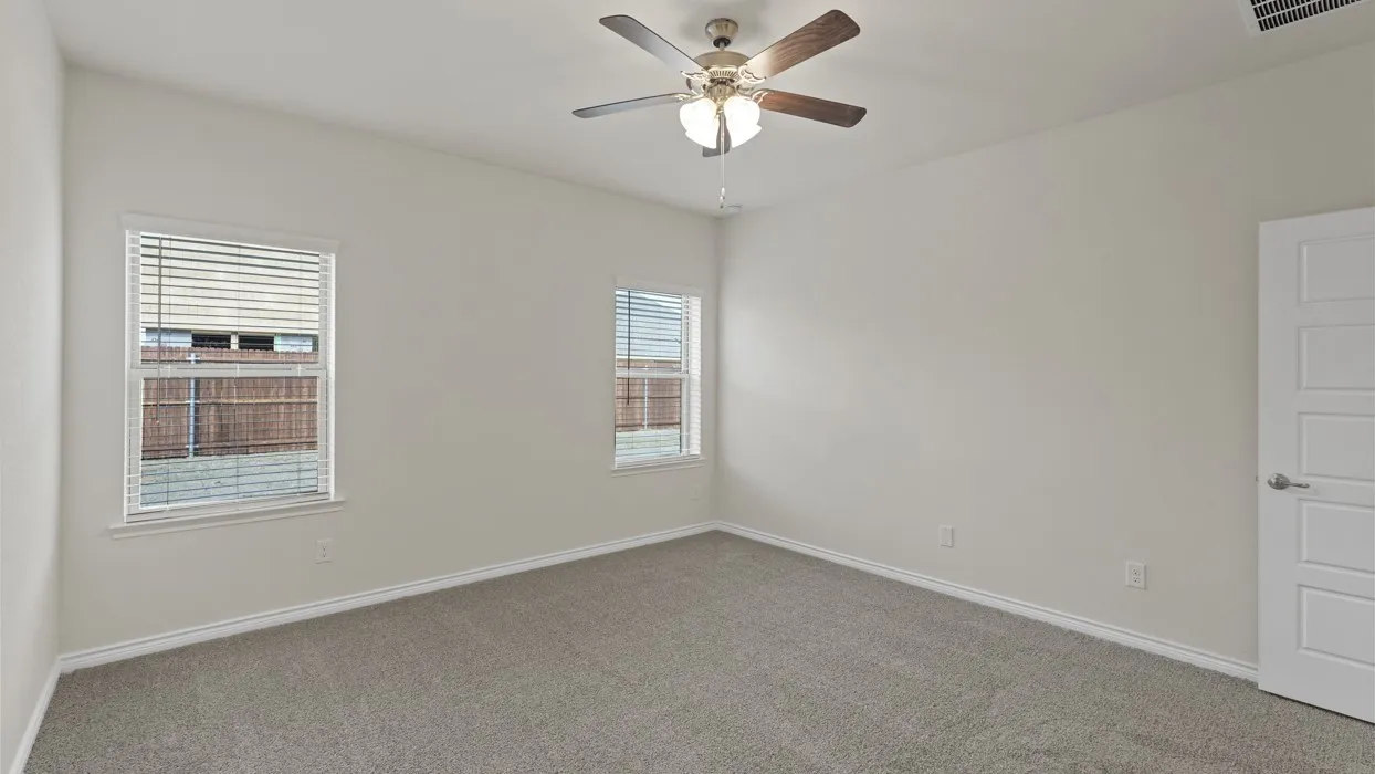 Carpeted interior room with white walls, two windows featuring horizontal blinds, and a ceiling fan with integrated lighting