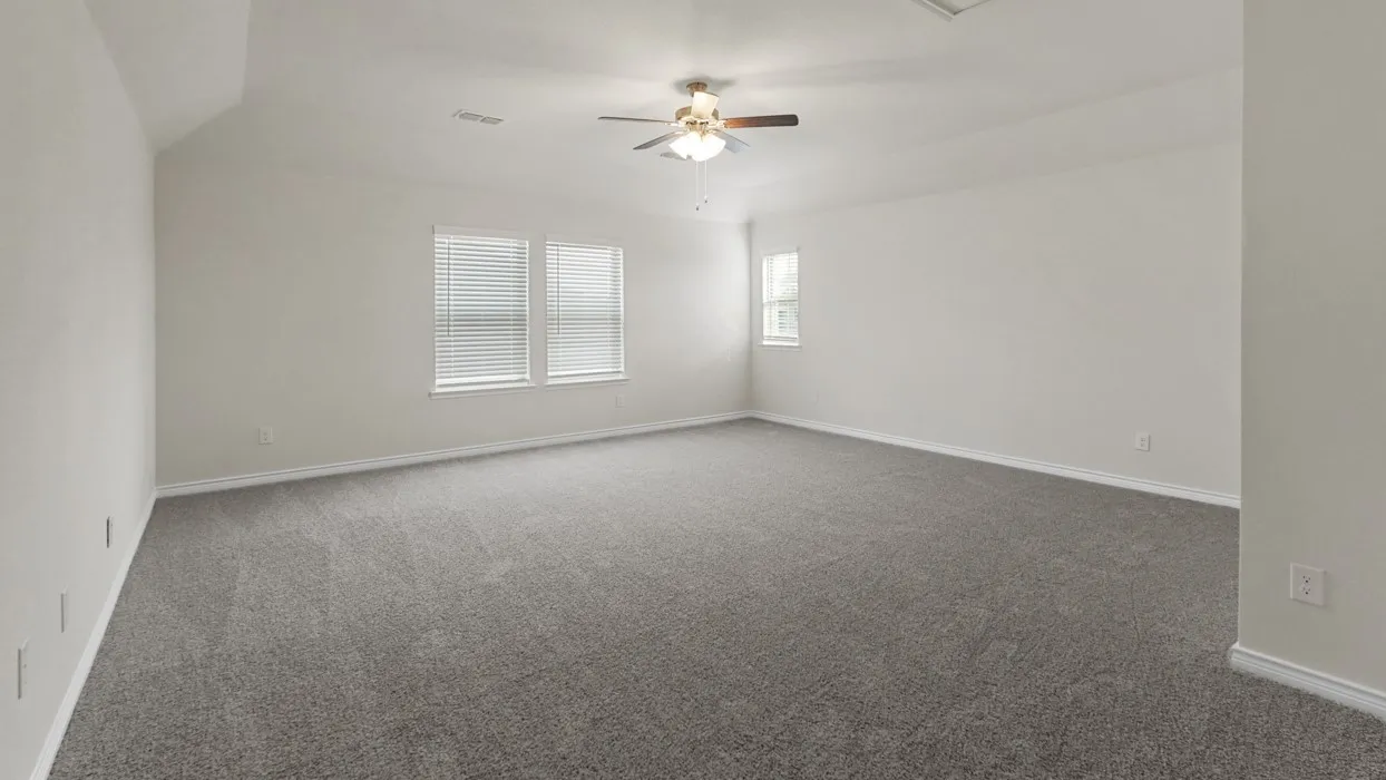 Spacious room featuring gray carpet, light-toned walls, and a ceiling fan with integrated lighting