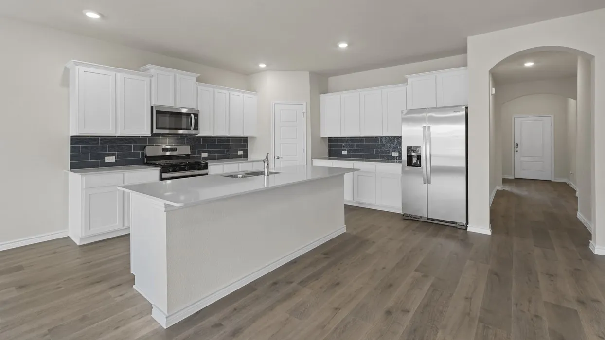 Modern kitchen featuring a central island with an undermount sink, white cabinetry, stainless steel appliances, and wood-finish flooring