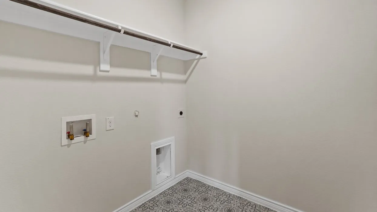 Laundry area featuring an overhead shelf with a clothing rod, patterned floor tiling, and neutral wall paint