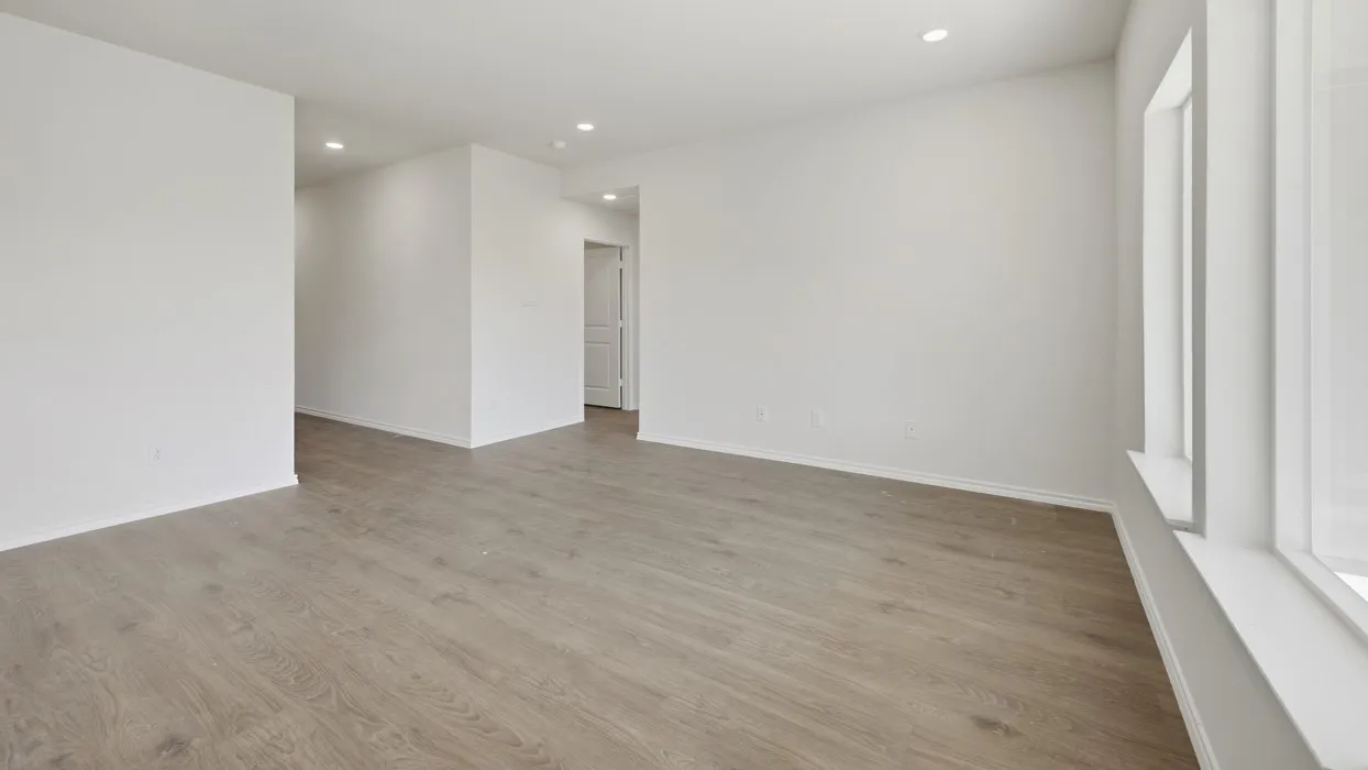 Spacious room featuring wood-finish flooring, recessed lighting, and large windows with white trim