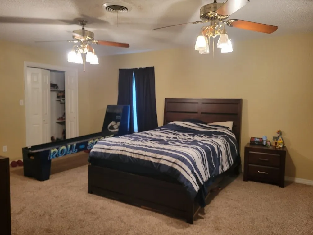 Plush carpet flooring, dual ceiling fans with integrated lighting, and a bi-fold closet door