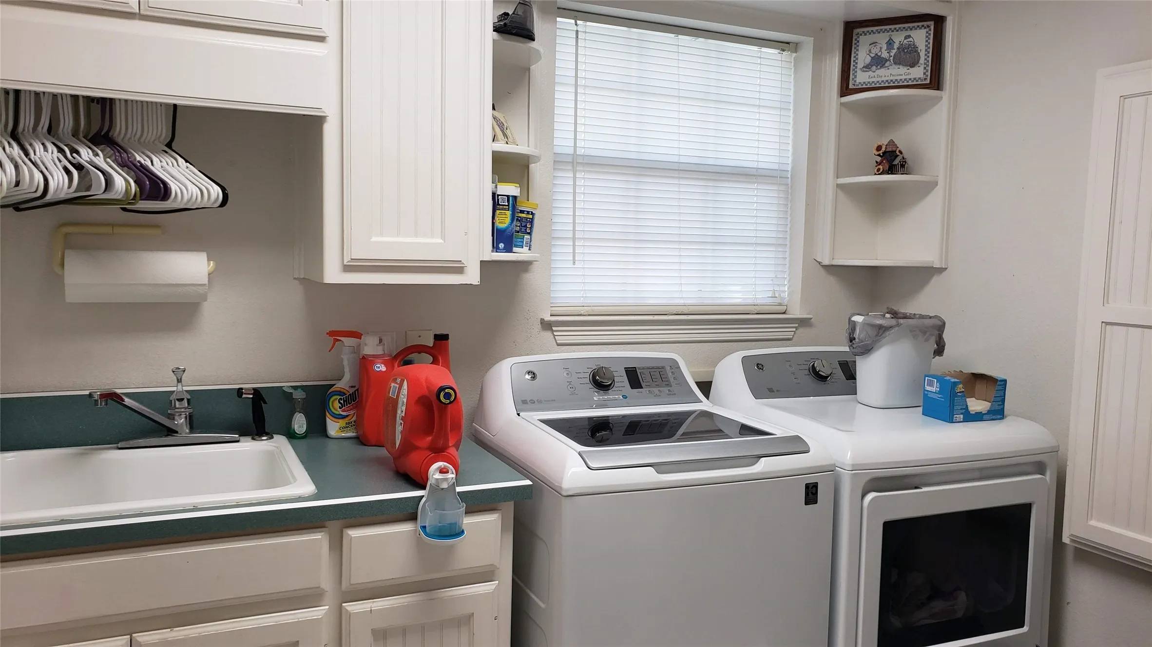 Dedicated laundry area featuring a utility sink, white cabinetry with beadboard paneling, and an upper hanging rod
