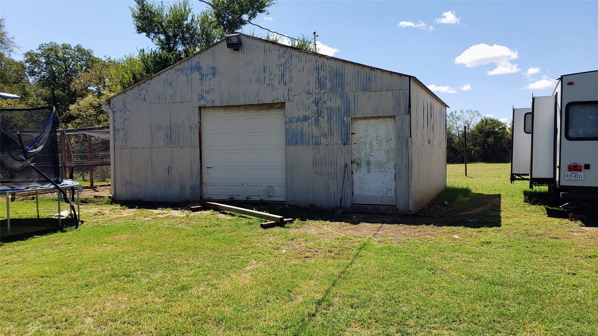 Corrugated metal utility building featuring a roll-up garage door and a side access door