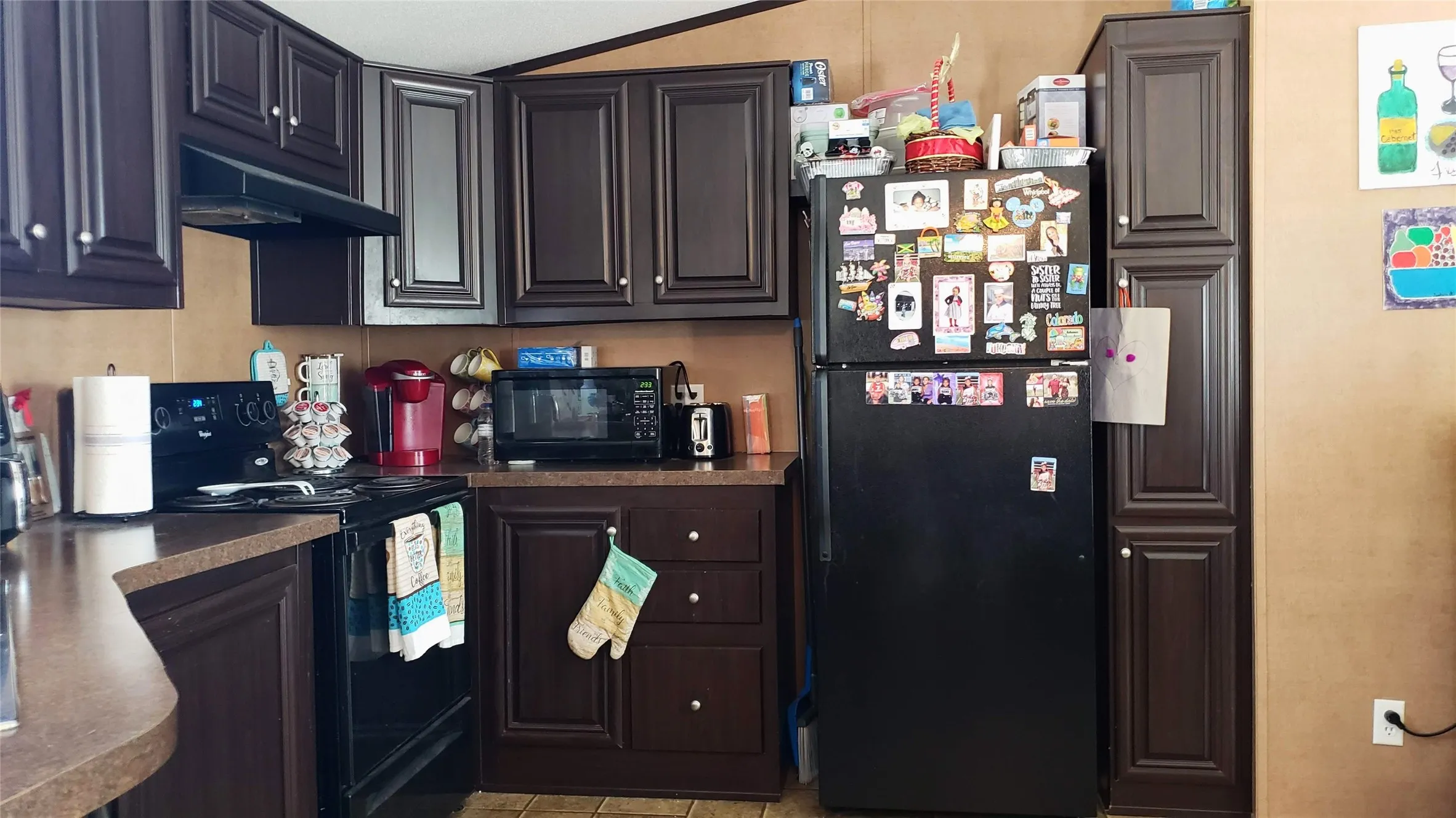 Mobile Kitchen featuring dark wood-finish cabinetry, black appliances, and a built-in microwave