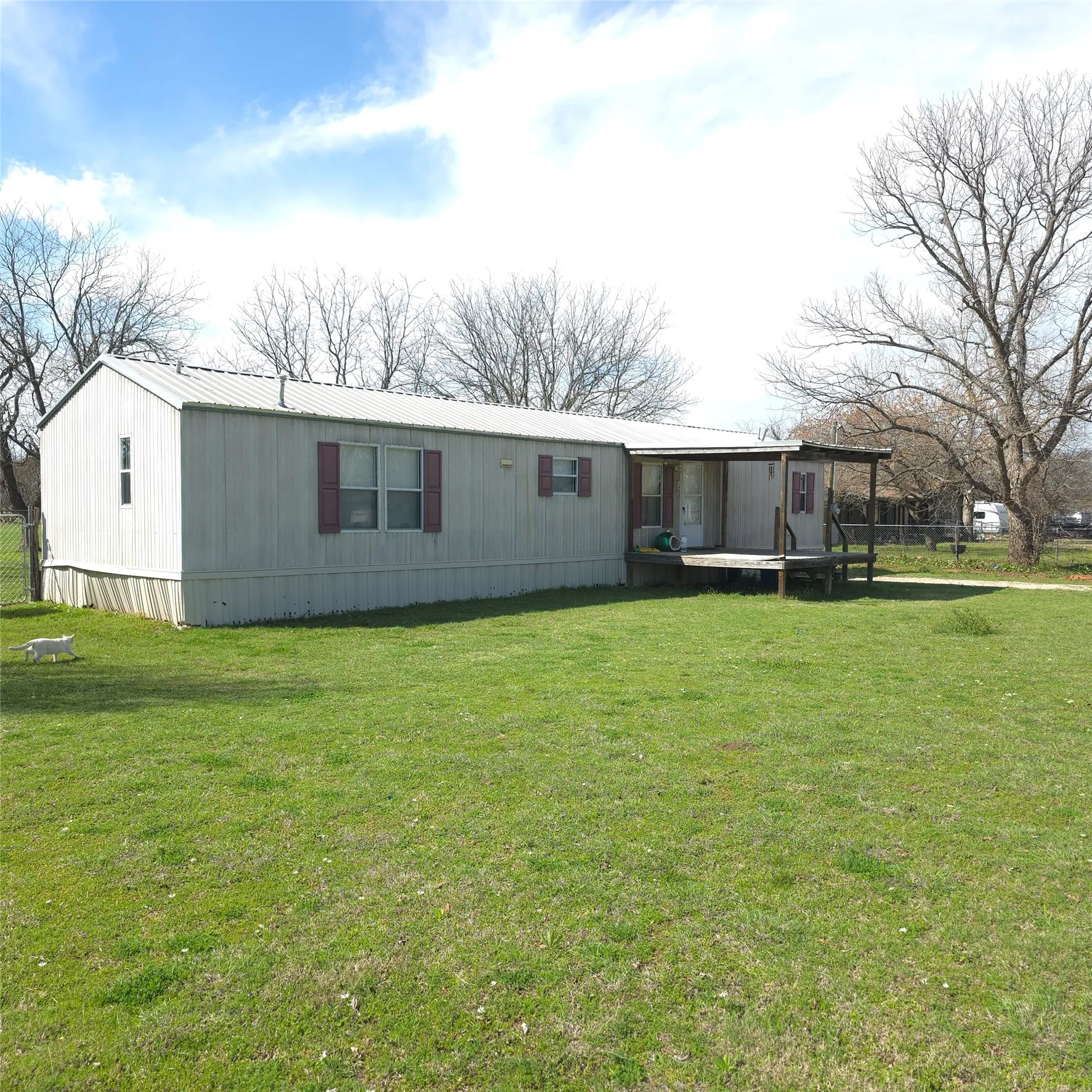 Expansive grass lawn bordered by mature trees and a chain-link fence