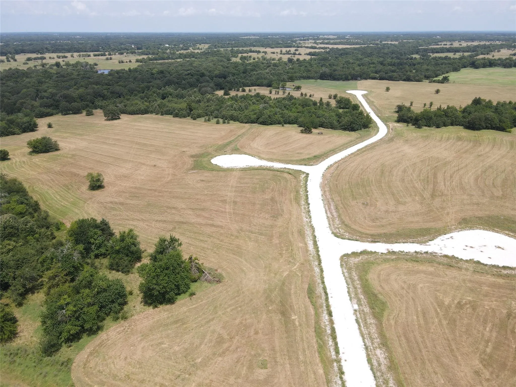 Expansive rural landscape featuring scattered trees, a developed road system, and visible land divisions