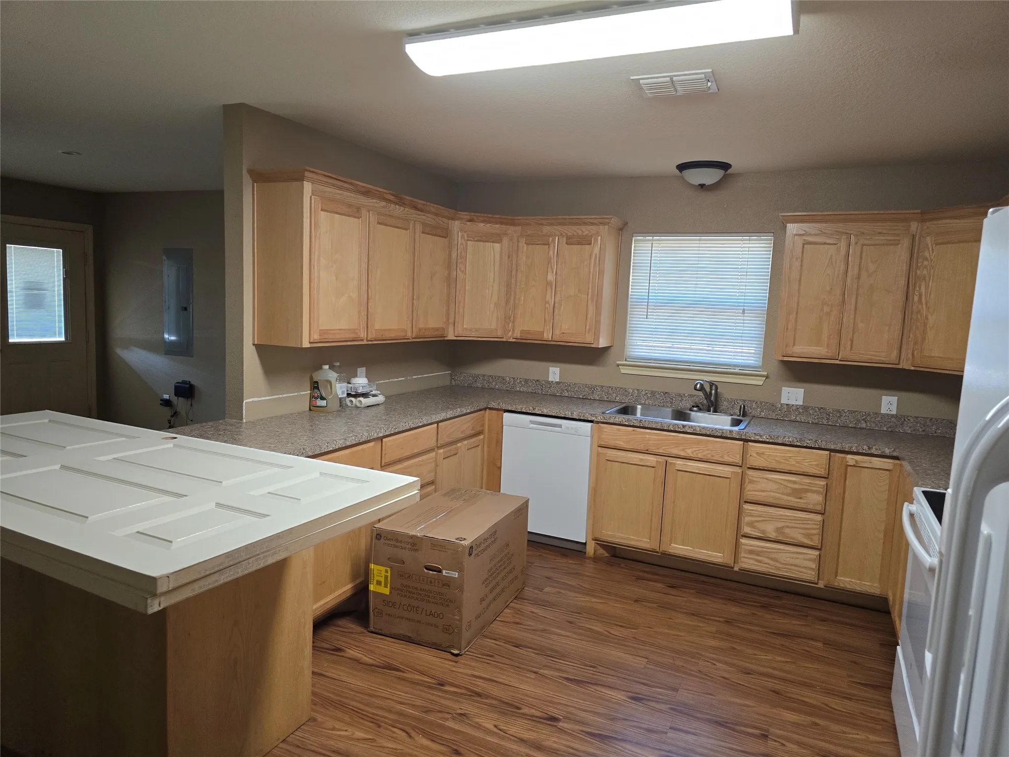 Kitchen featuring wood-finish flooring, wood cabinetry, a double basin sink, and laminate countertops