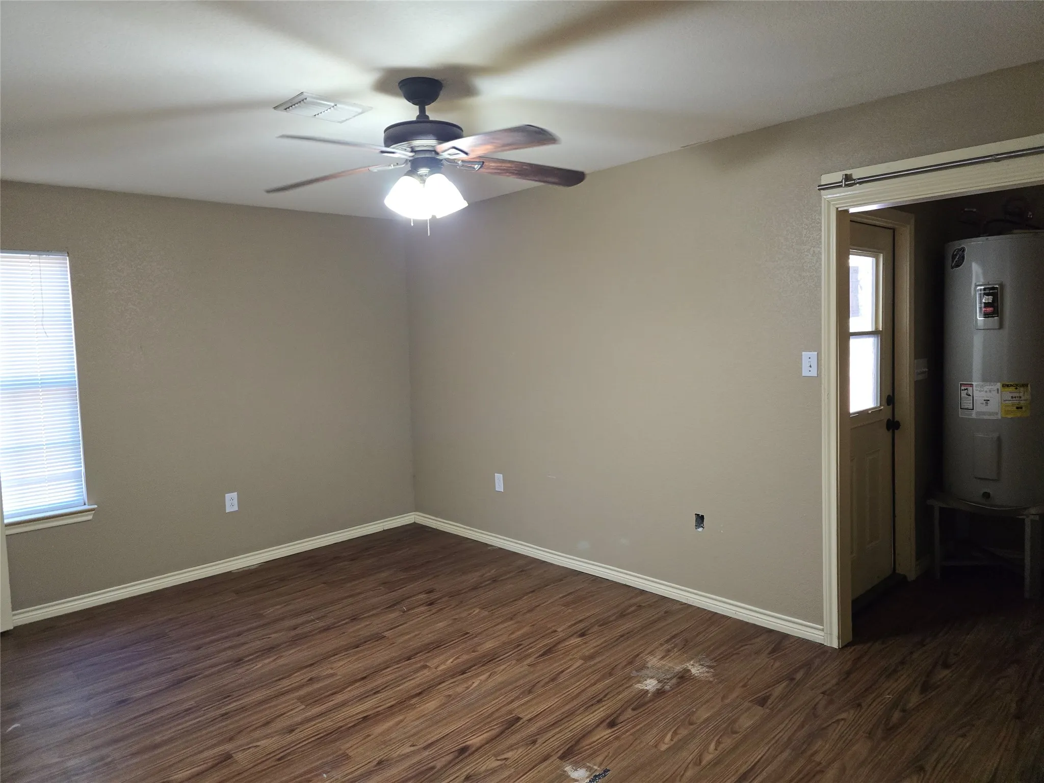 Wood-finish flooring, ceiling fan with integrated lighting, neutral wall tones, and white window blinds