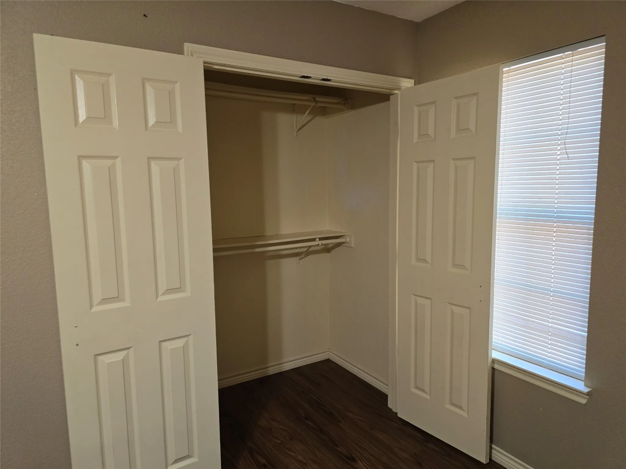 Closet with bi-fold paneled doors, built-in shelving, and wood-finish flooring