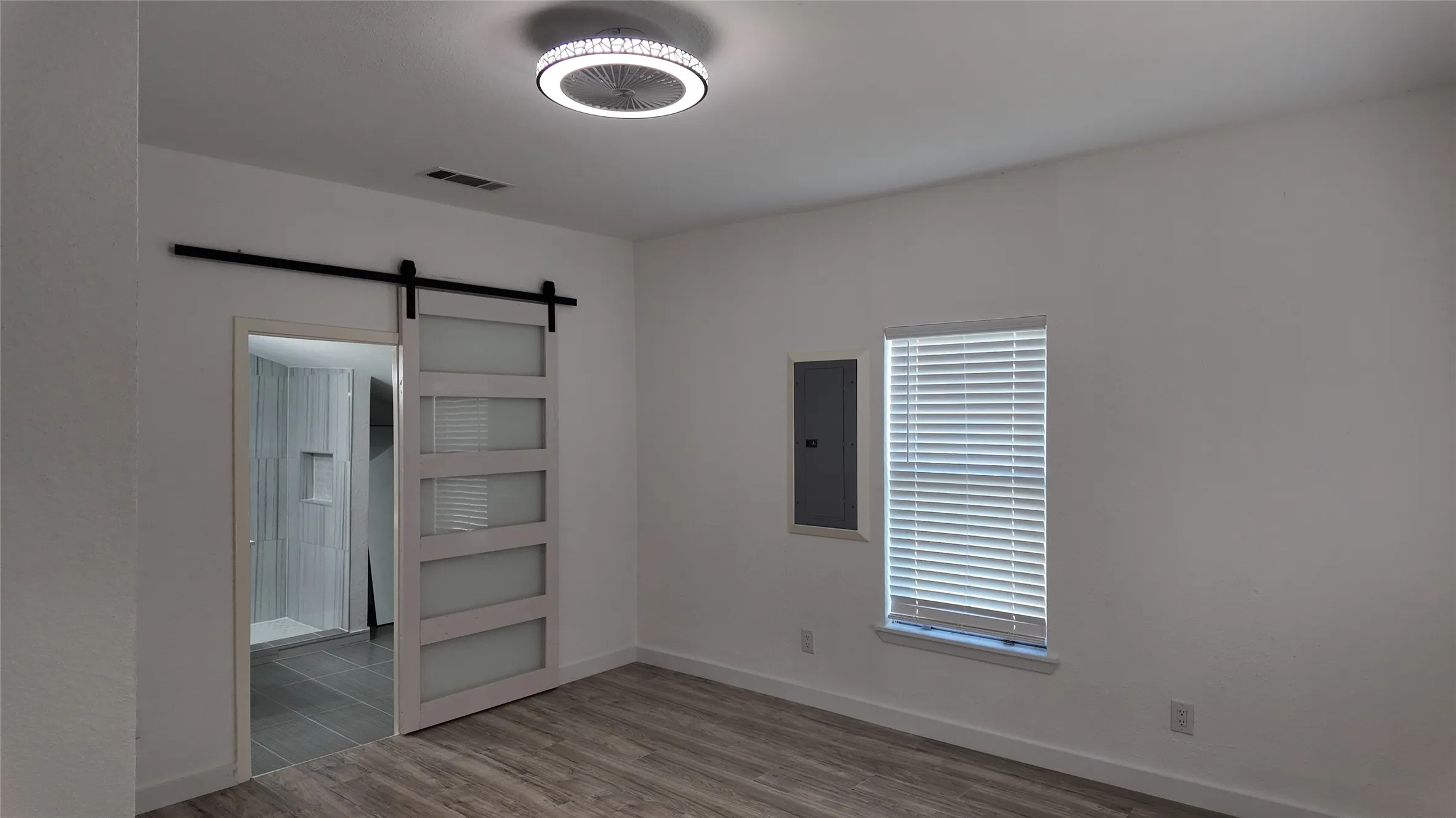 Wood-finish flooring, white walls, and a window with blinds