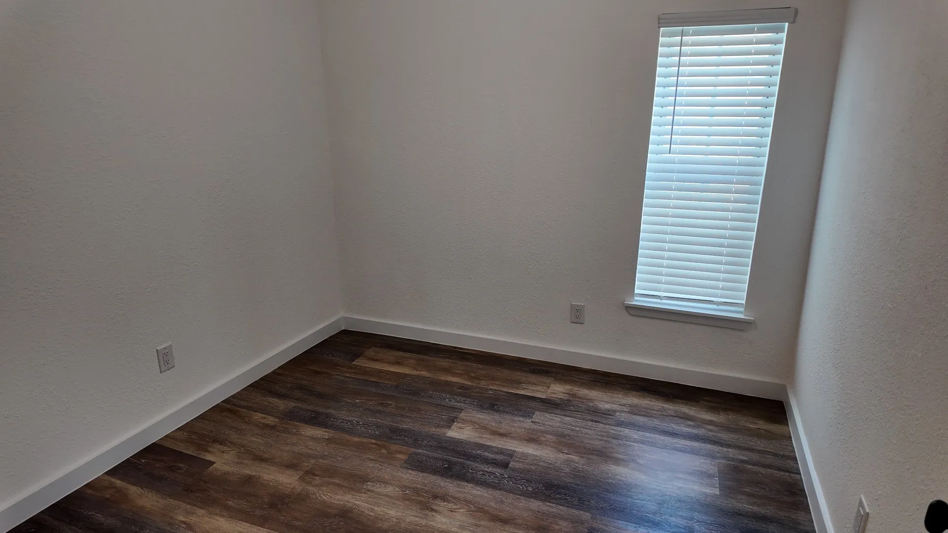 Wood-finish flooring with white baseboards and light-toned walls