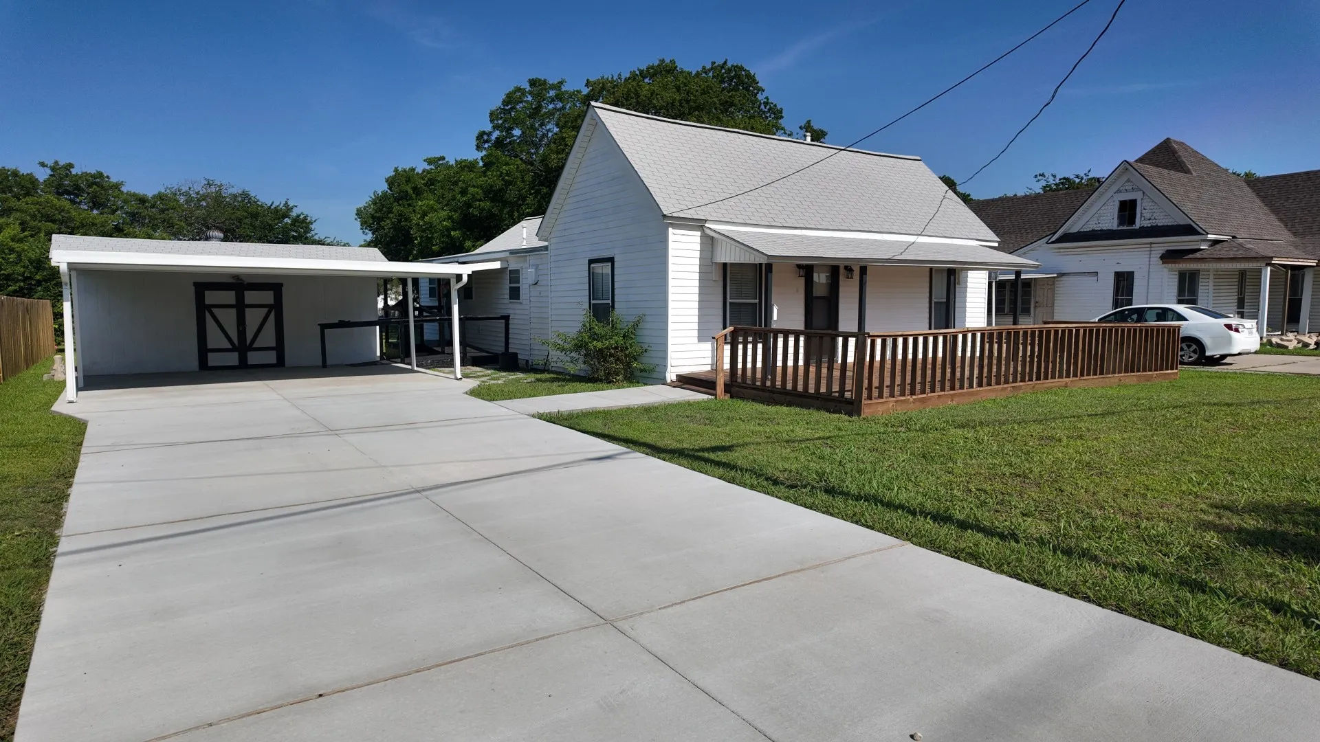 White siding exterior with a metal roof and an extended wooden deck
