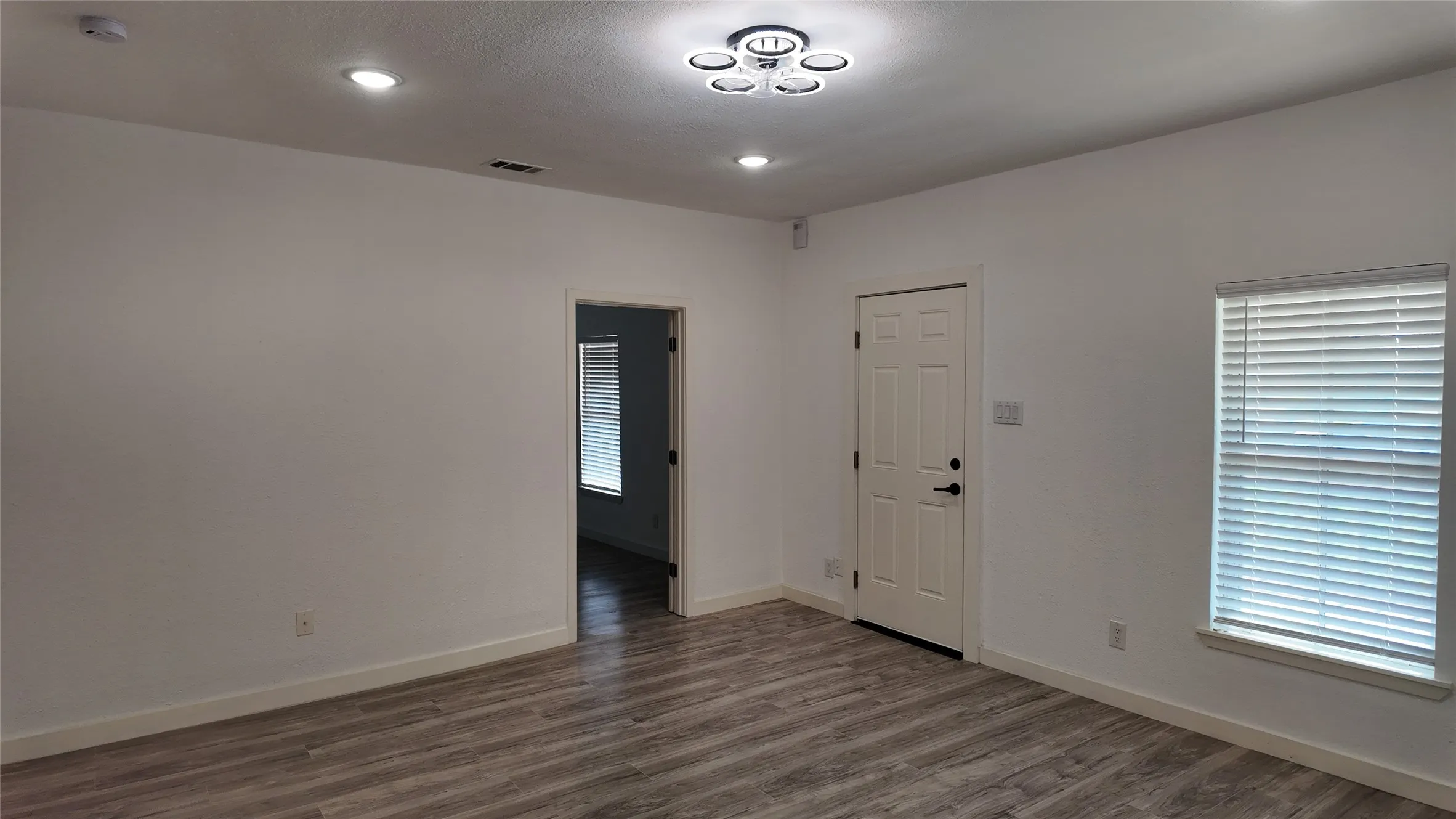 Wood-finish flooring throughout, paired with white walls, recessed lighting, and a modern ceiling fixture