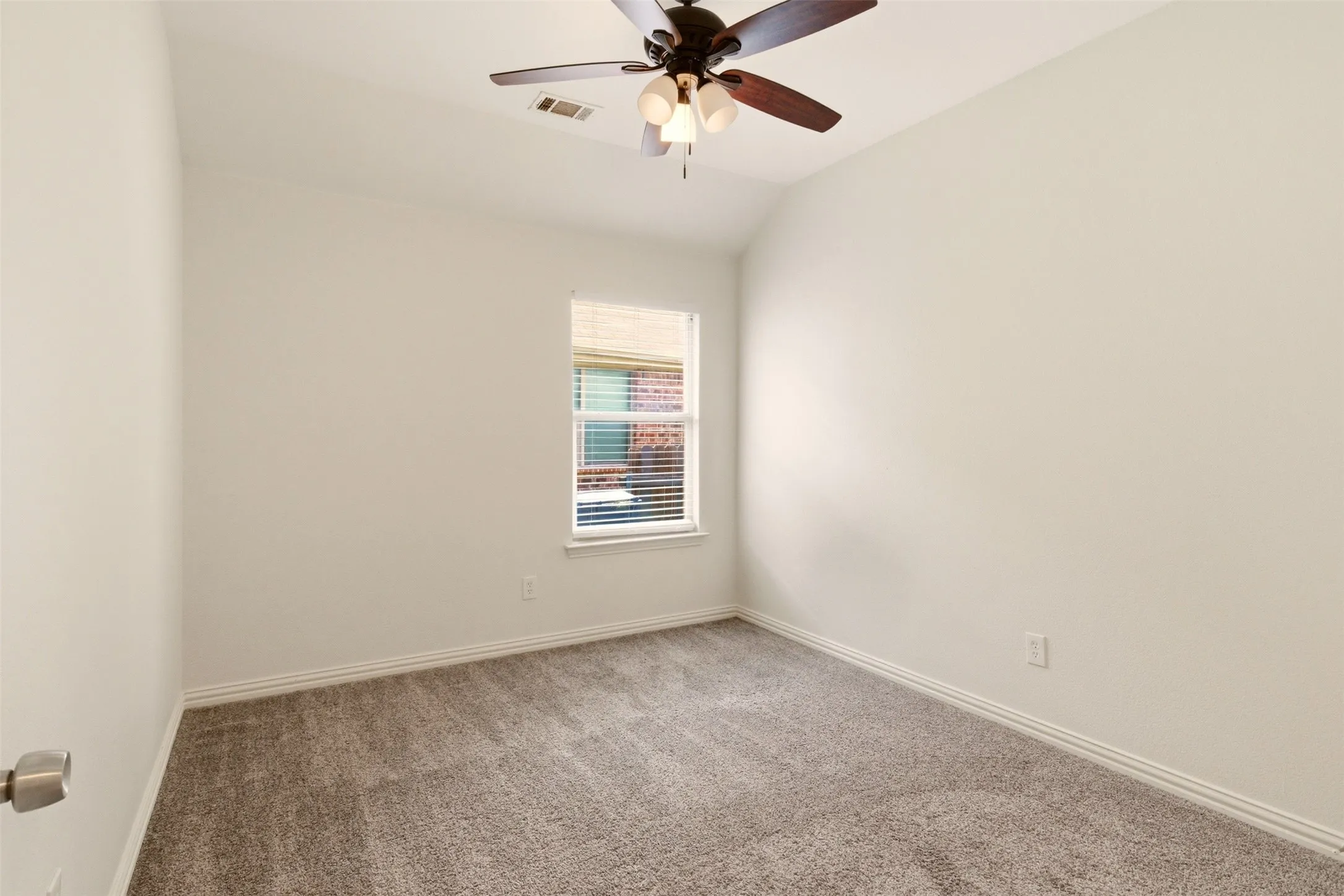 Neutral wall color, carpeted flooring, window with blinds, and a ceiling fan with integrated lighting