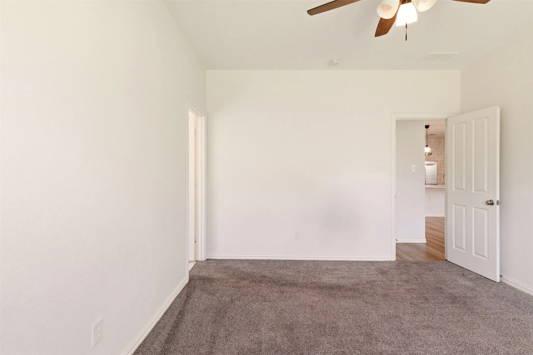 Ceiling fan with integrated lighting, neutral carpet flooring, white walls, and white trim