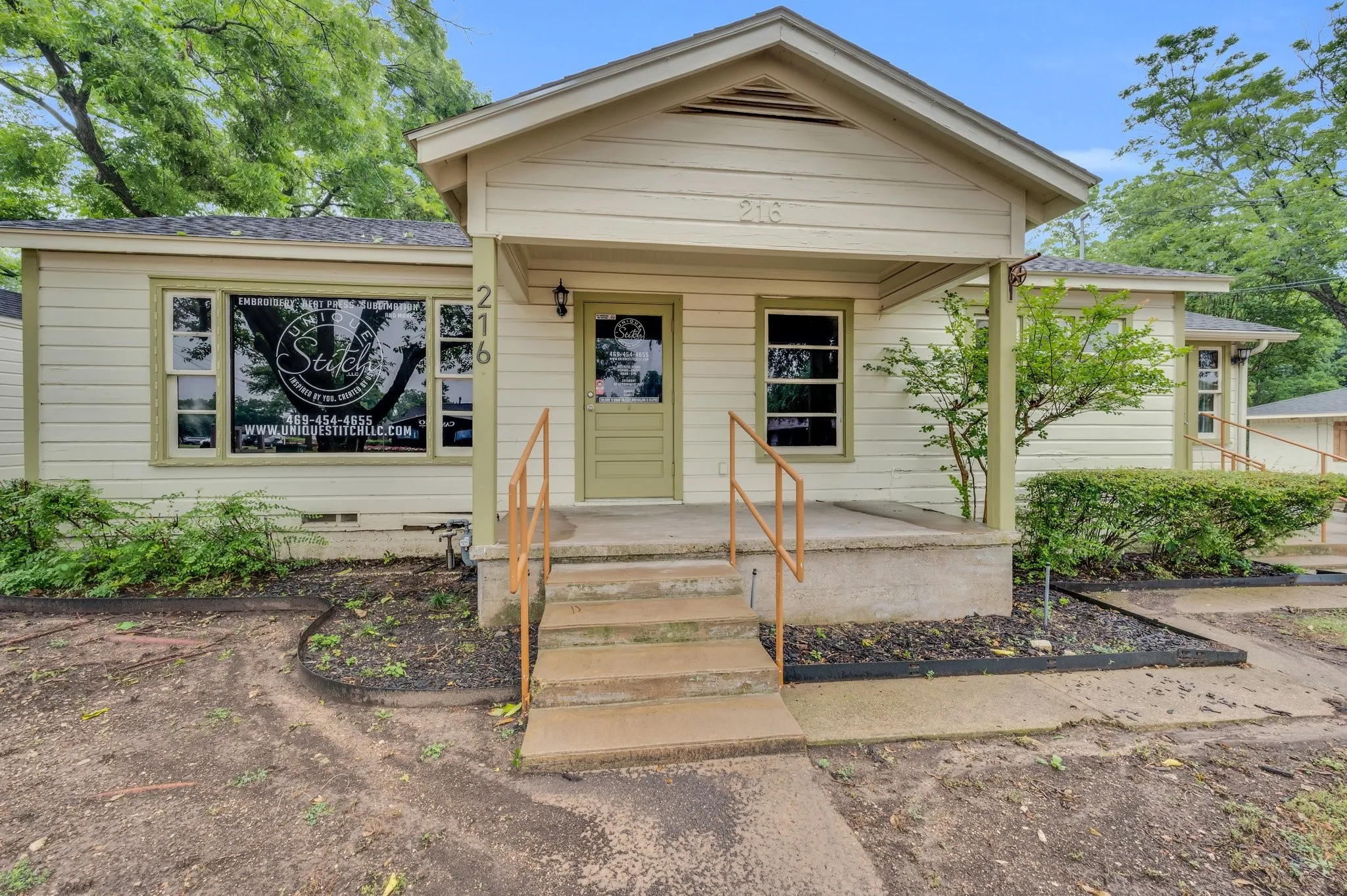 Front facade featuring a covered porch with concrete steps and a handrail, multiple windows, and a prominent front door