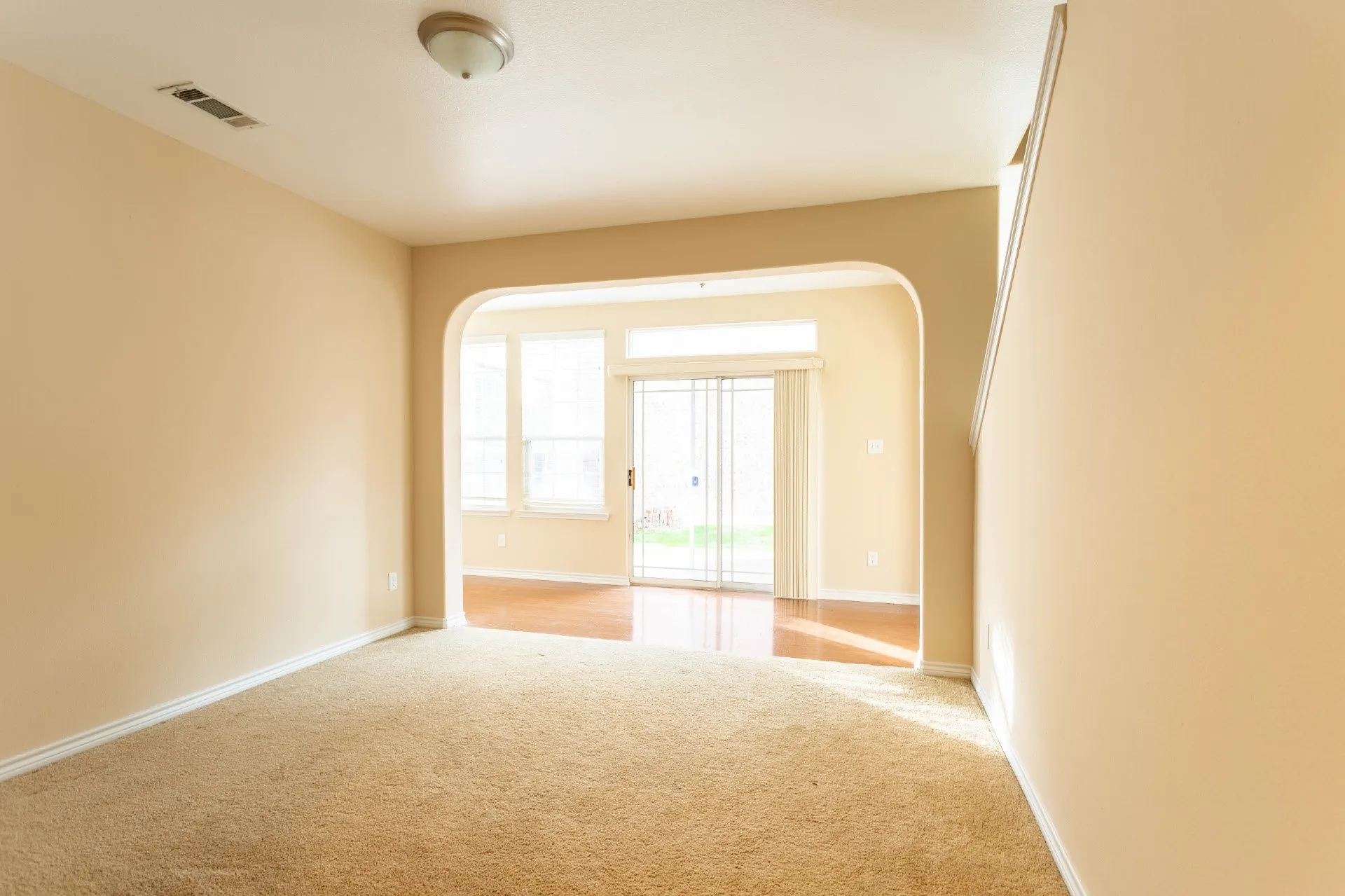 Archway entry to a room featuring wood-finish flooring, multiple windows, and a sliding glass door