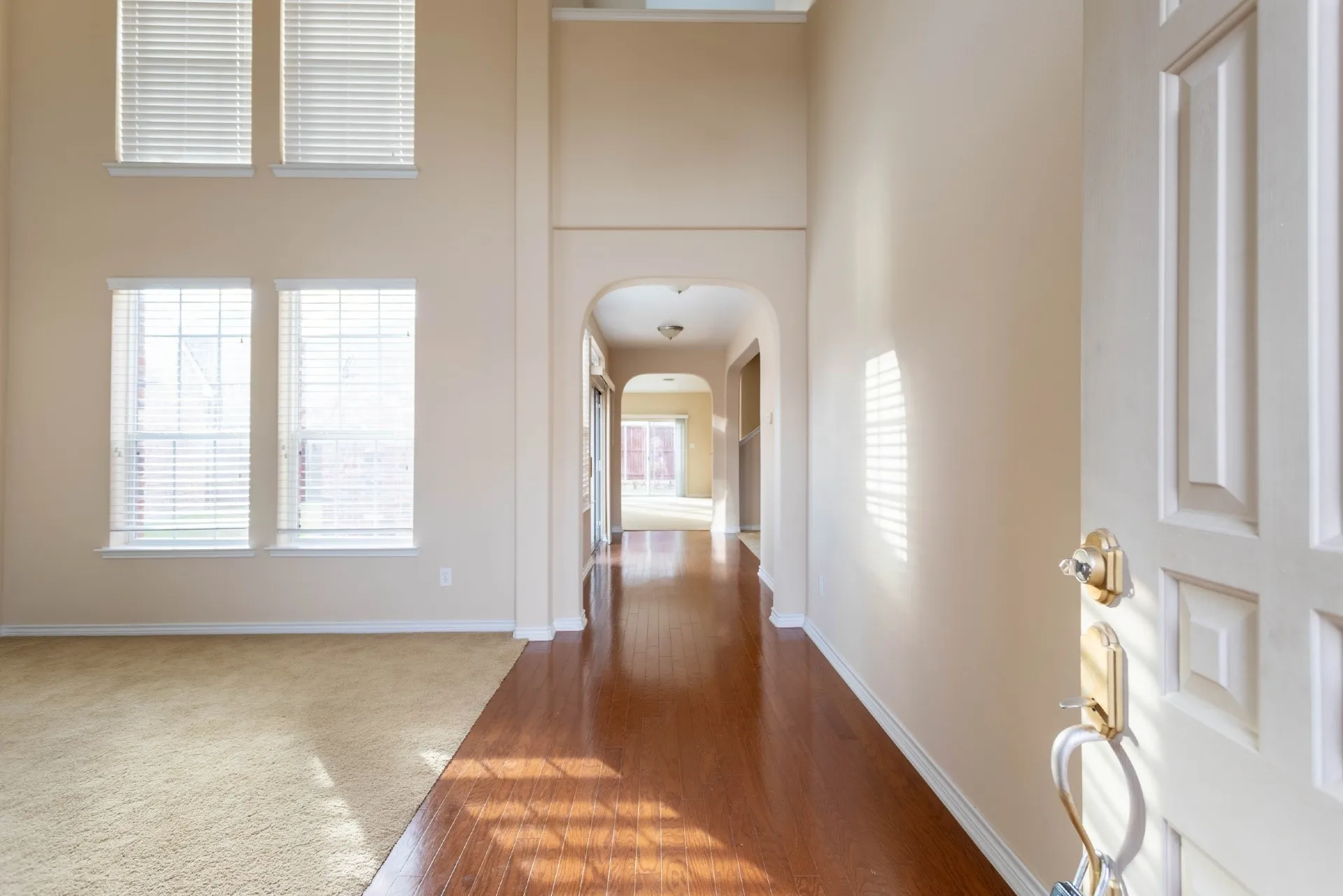 Two-story entryway with wood-finish flooring, arched doorway, and tall windows