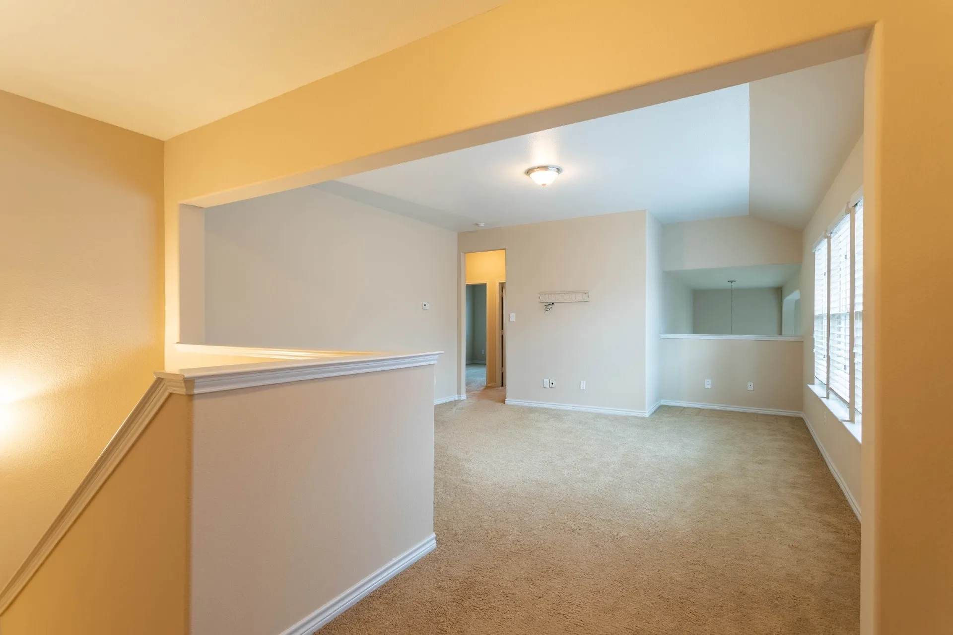 Carpeted living area with abundant natural light, multiple windows with blinds, and recessed lighting