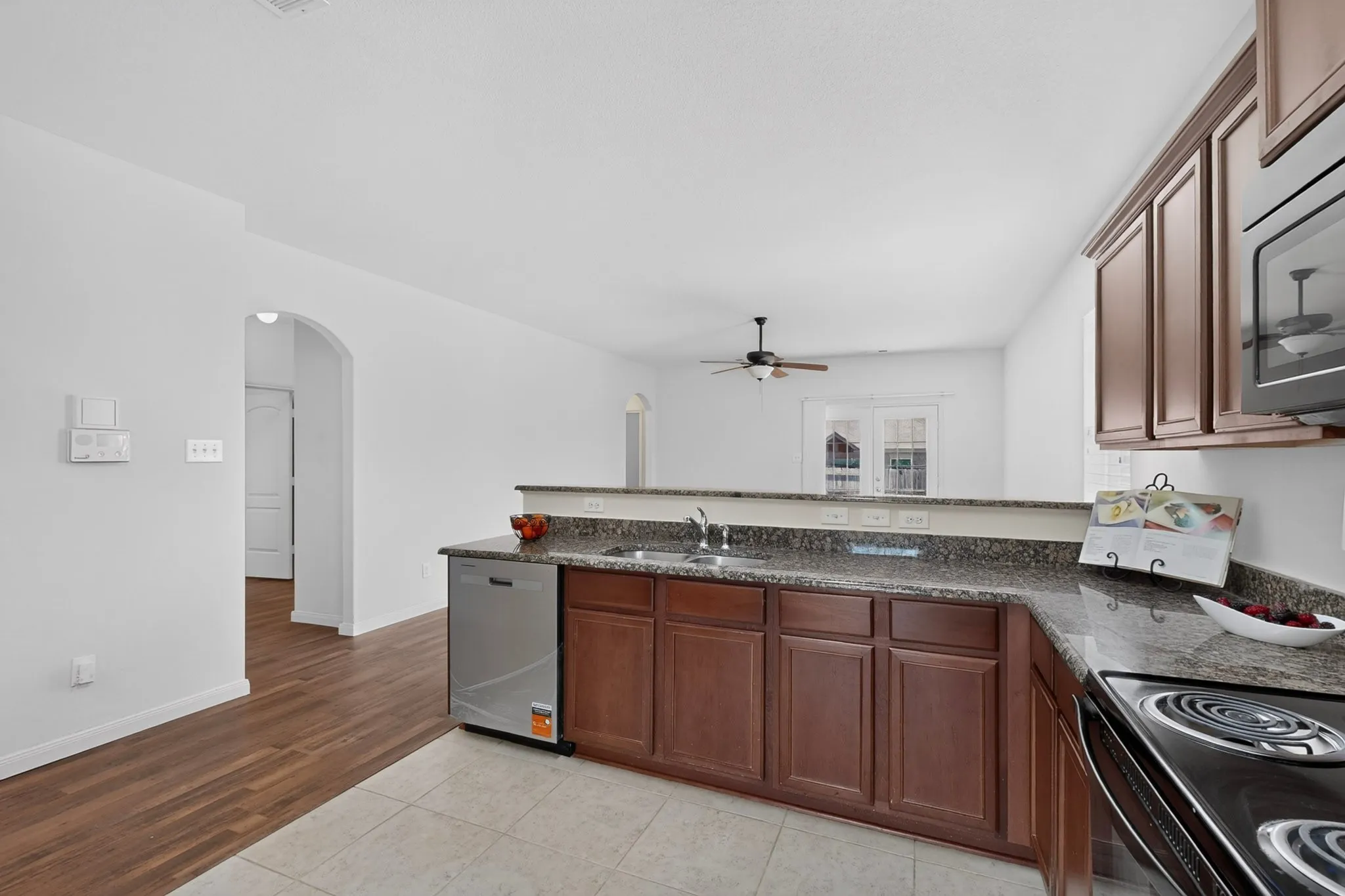 Kitchen featuring a stainless steel dishwasher, brown cabinetry, and speckled countertops