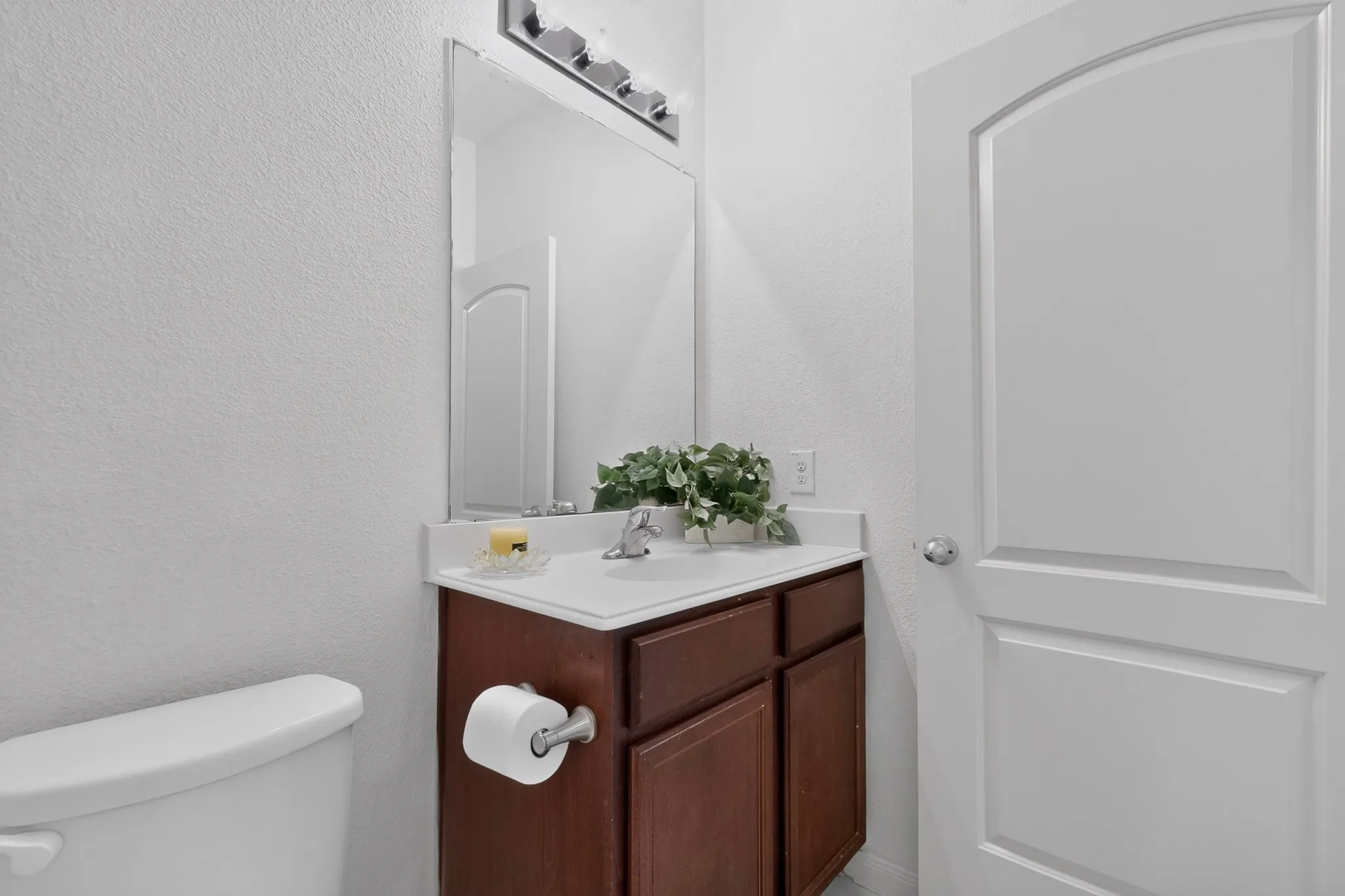 White paneled door with an arched top frame, chrome door hardware, wood-finish vanity with a white countertop and integrated sink, and a chrome faucet