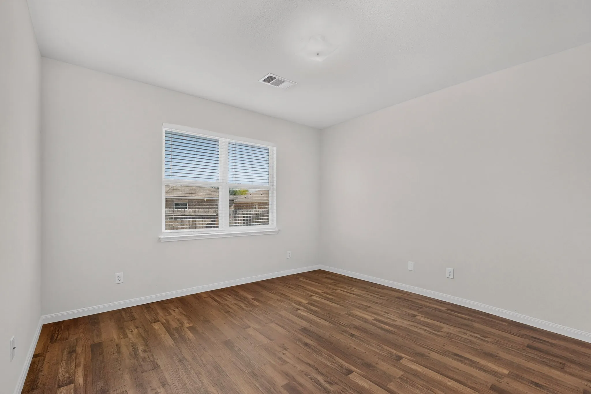 Wood-finish flooring with white baseboards and light-toned walls