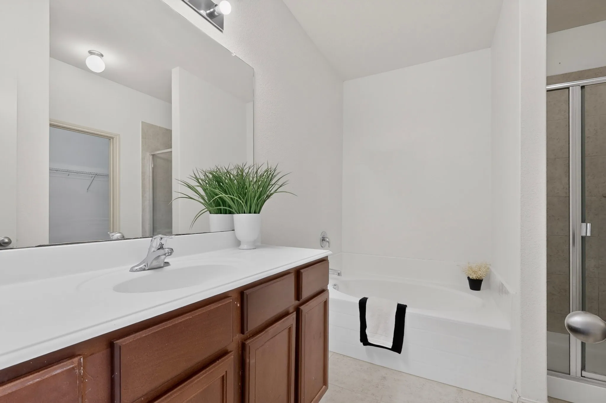 Integrated vanity with a single basin, dark wood-finish cabinetry, and a full-width mirror