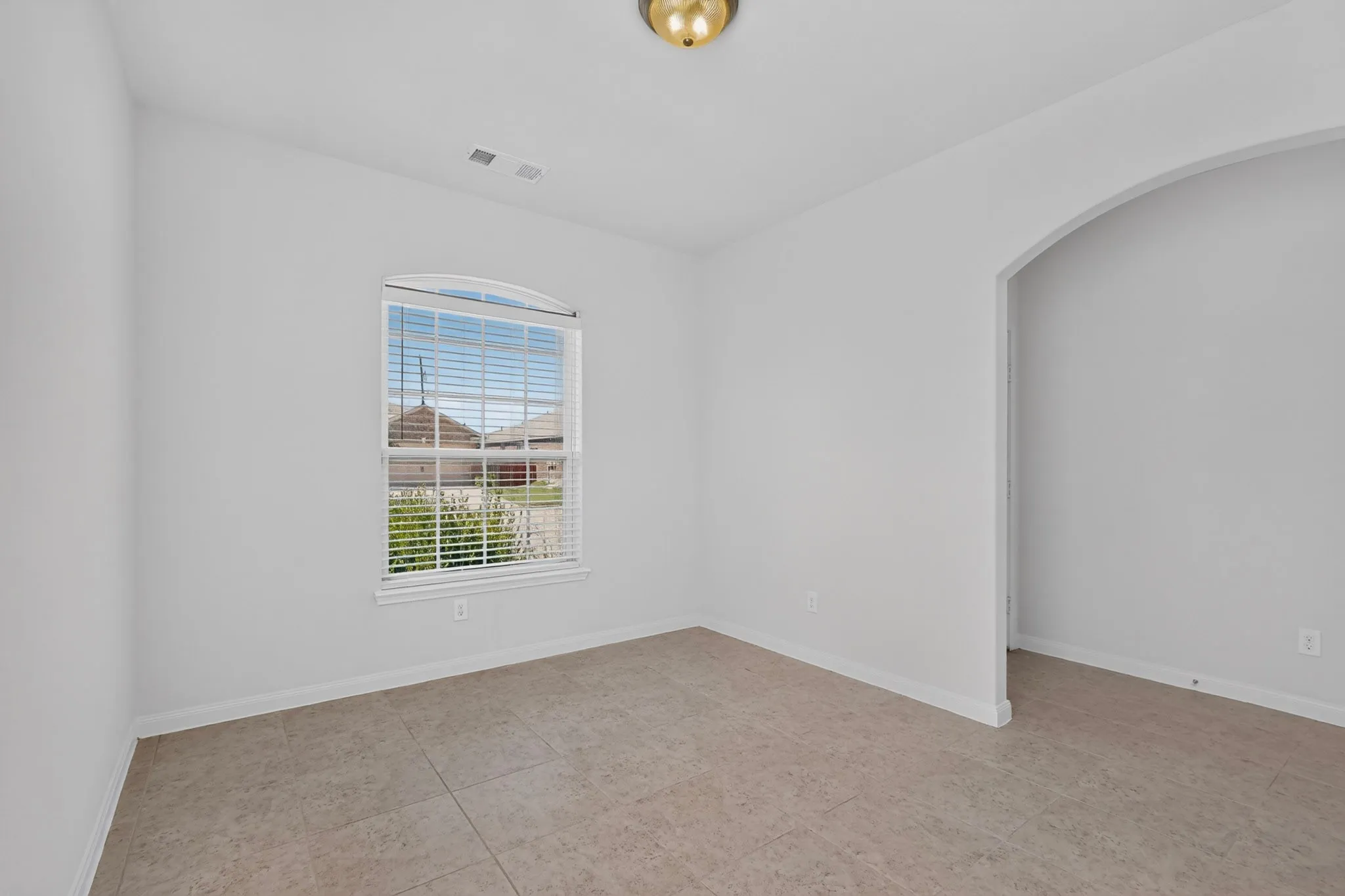 Arched entryway, tiled flooring, arched window with horizontal blinds, and a flush mount ceiling light