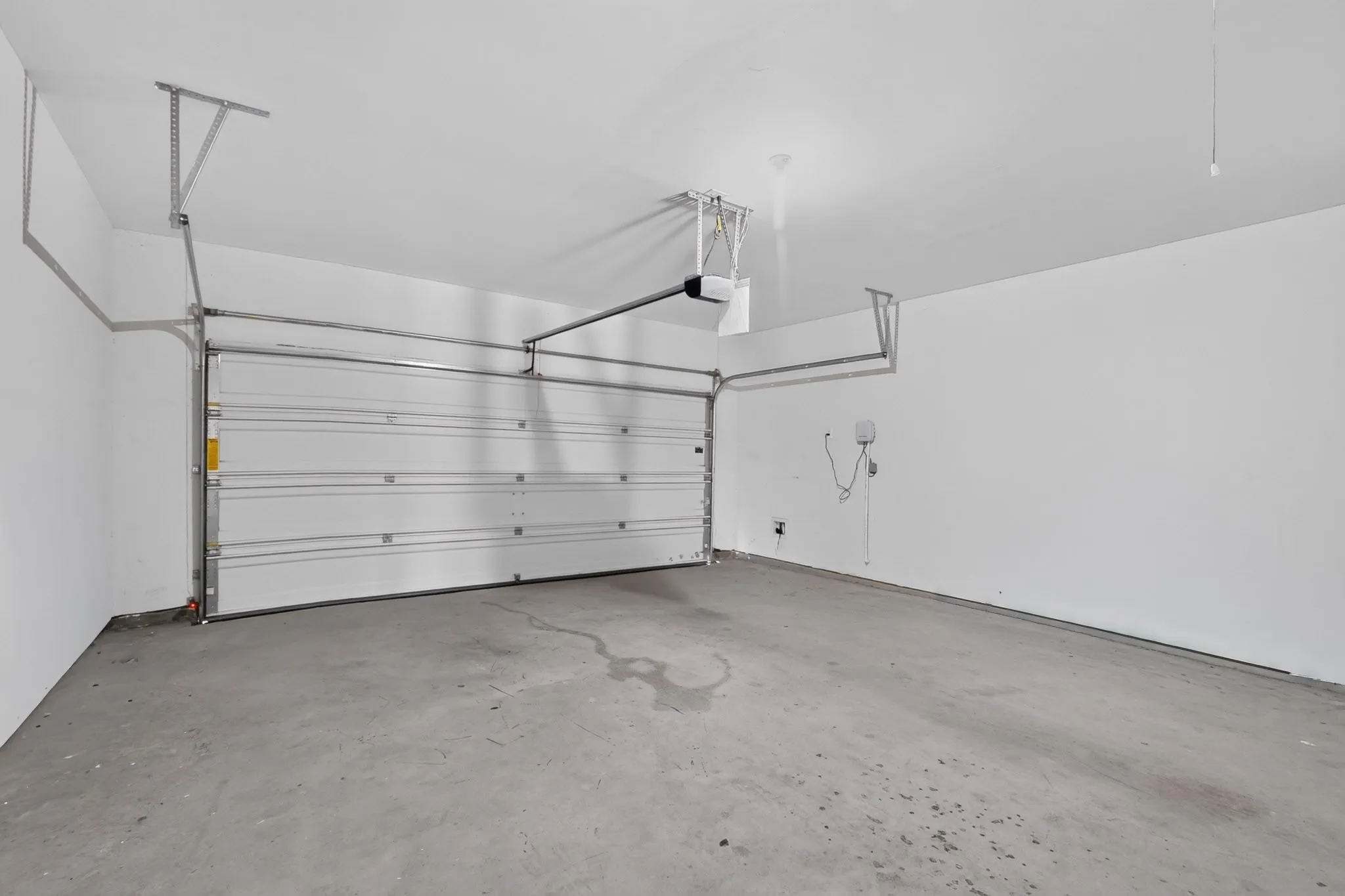 Spacious garage with a concrete floor, white painted walls, and an overhead garage door system