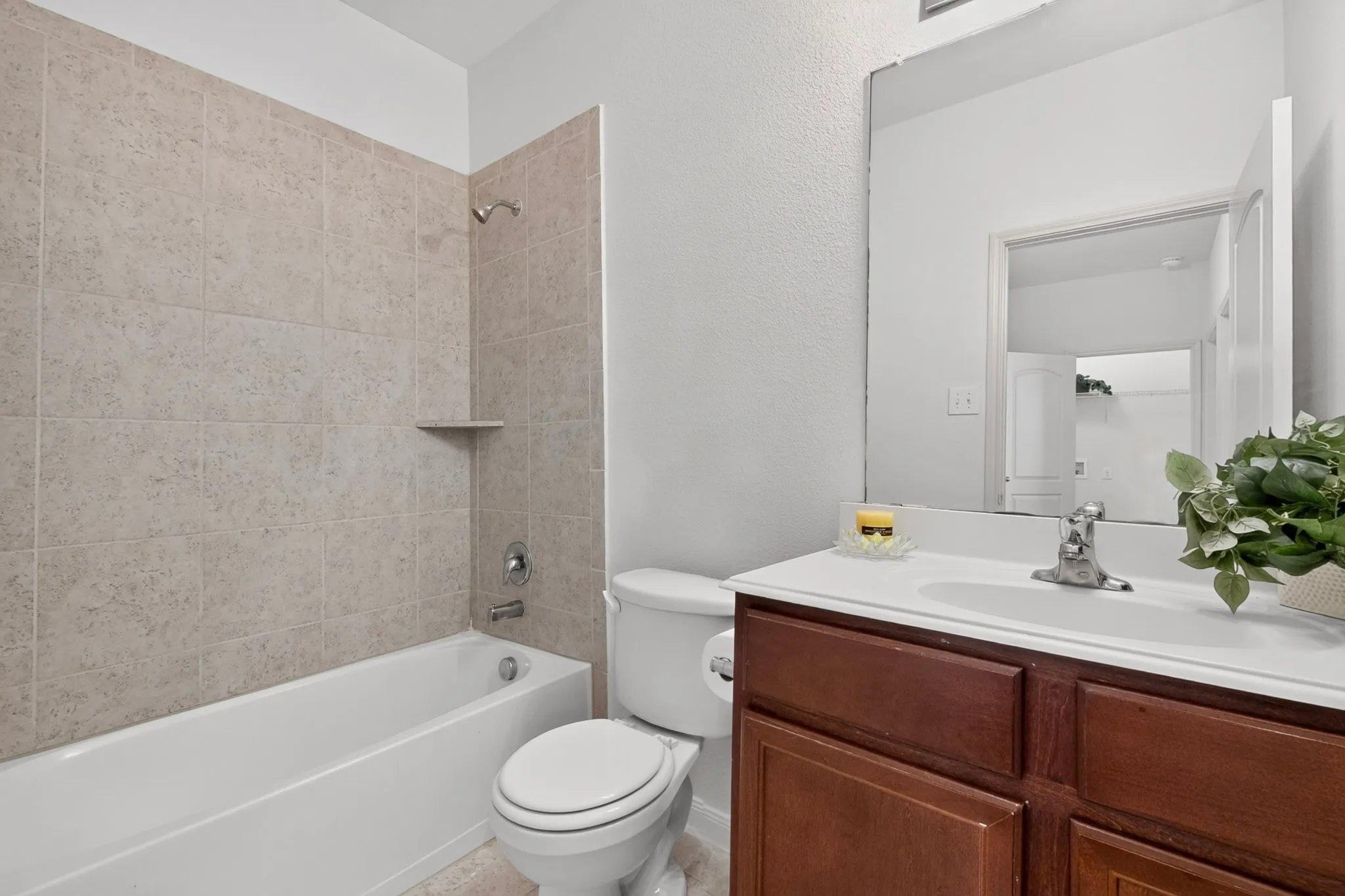 White bathtub with light-colored tile surround and built-in shelf