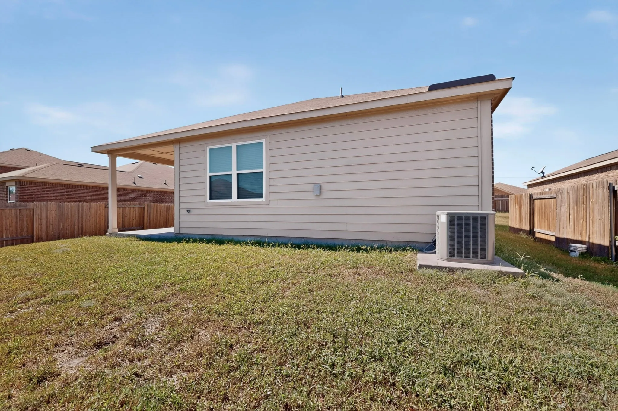 Backyard featuring an extended covered patio, perimeter fencing, a window with white trim, and vinyl siding