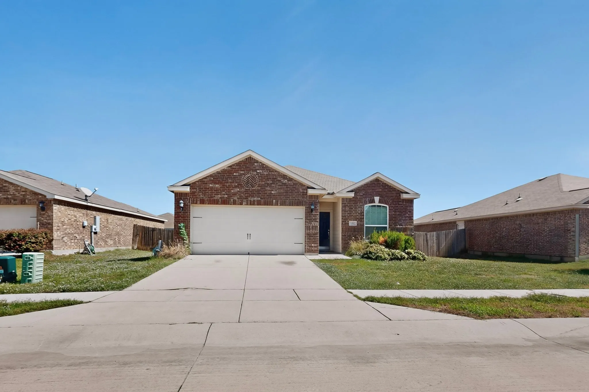 Brick exterior with an attached two-car garage, concrete driveway, and front lawn
