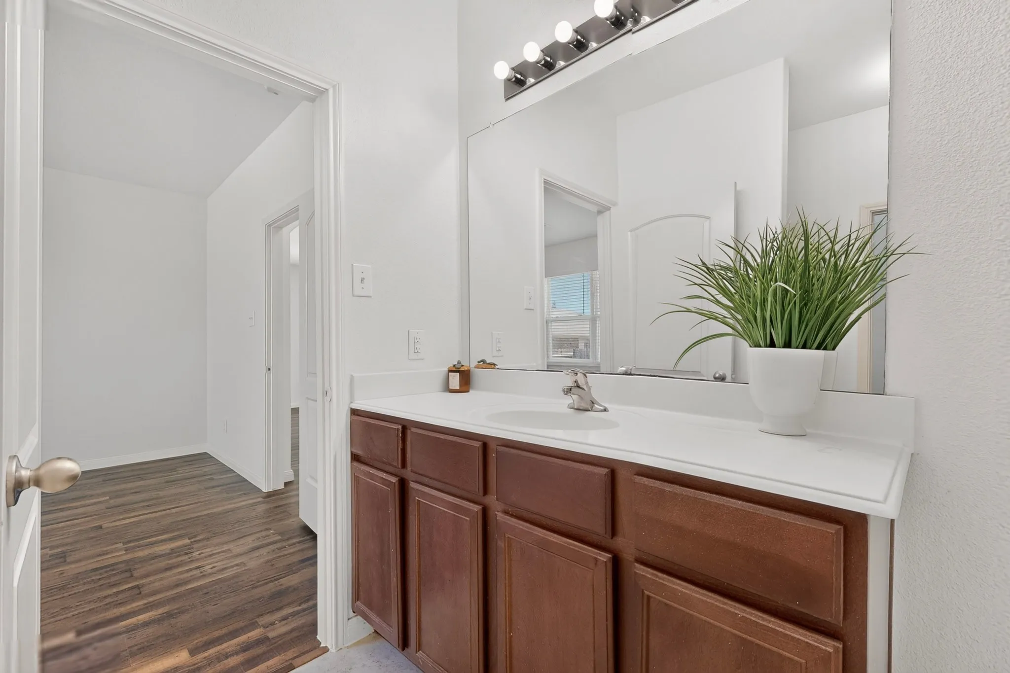 Bathroom vanity with a white countertop, under-mount sink, and wood-finish cabinetry